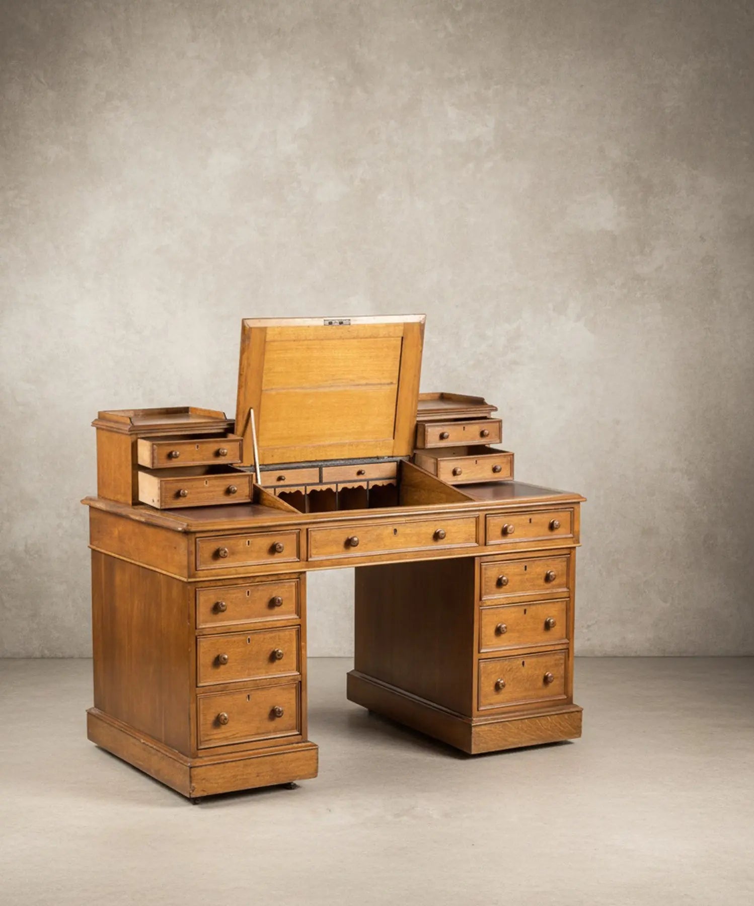 Escritorio antiguo tipo Dickens de roble con cajones de los pedestales abiertos mostrando construcción artesanal.