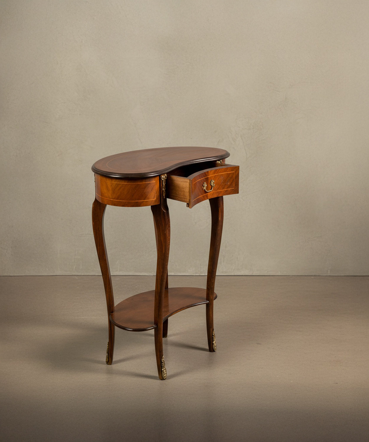 Mesa auxiliar de madera en forma de riñón con cajón abierto, mostrando el detalle de la marquetería y patas cabriolé.