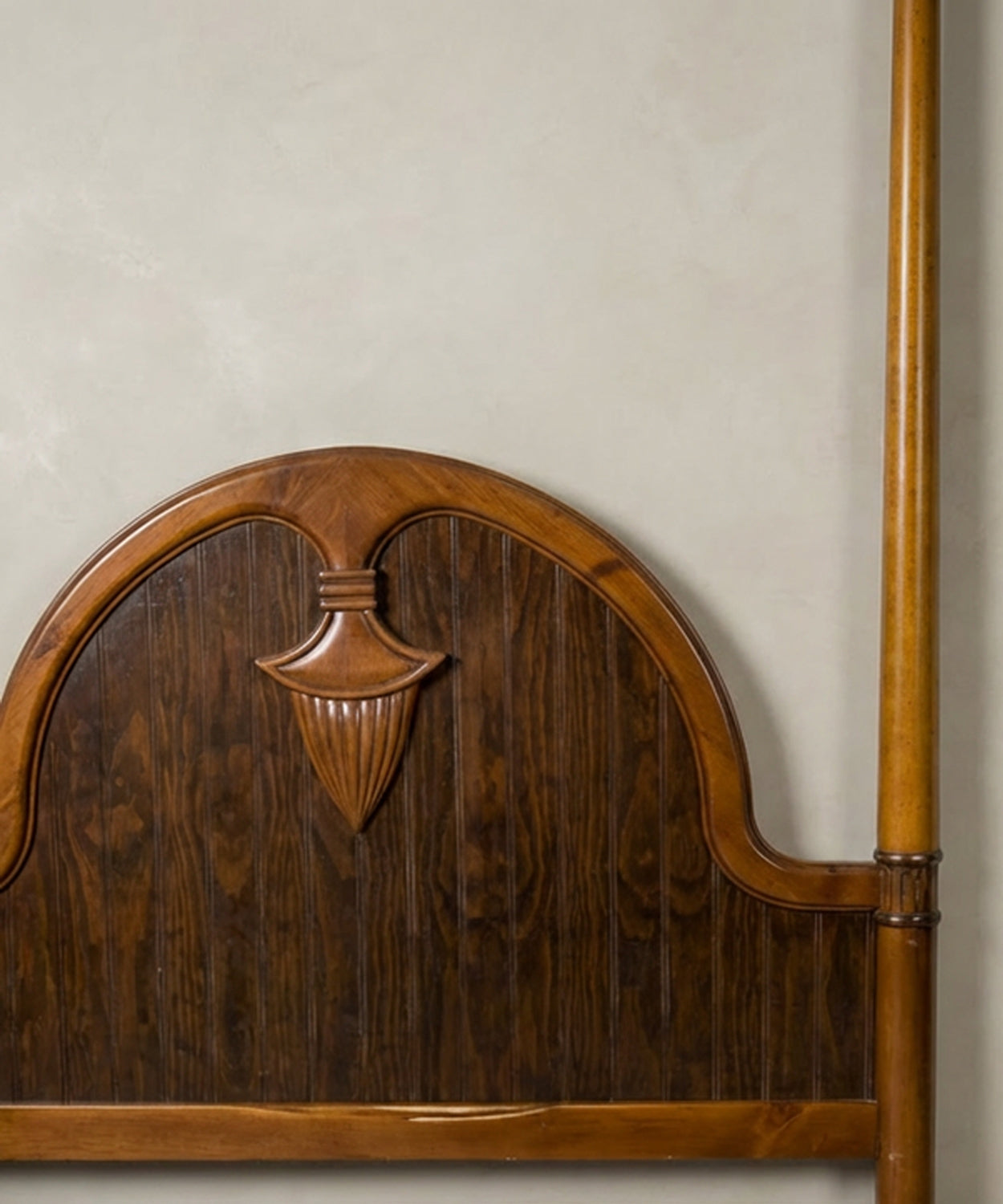Primer plano del cabecero arqueado mostrando la talla central artesanal y el contraste de vetas de madera.