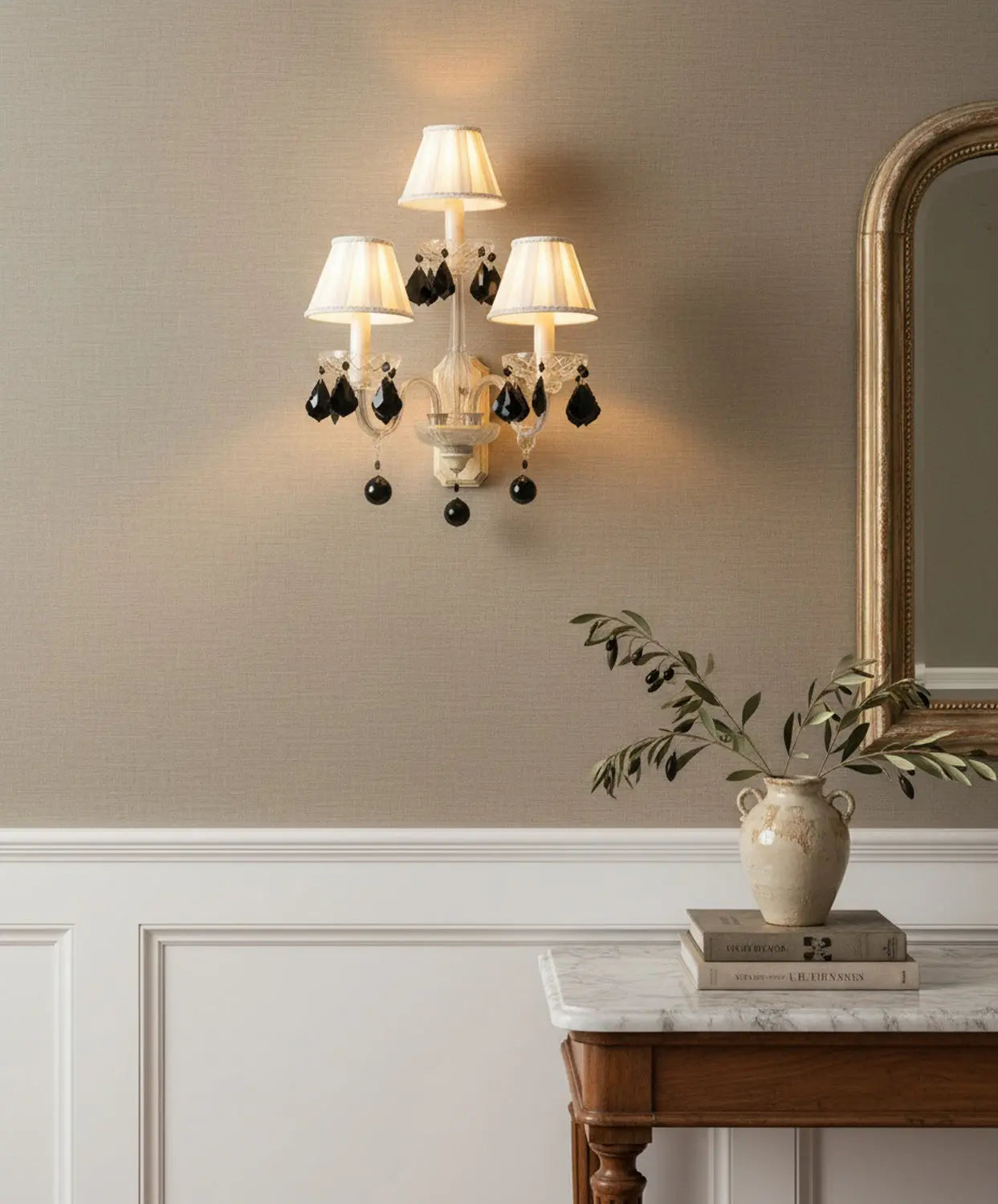 Aplique de pared vintage de 3 luces con brazos de cristal y lágrimas negras colgantes sobre pared beige.