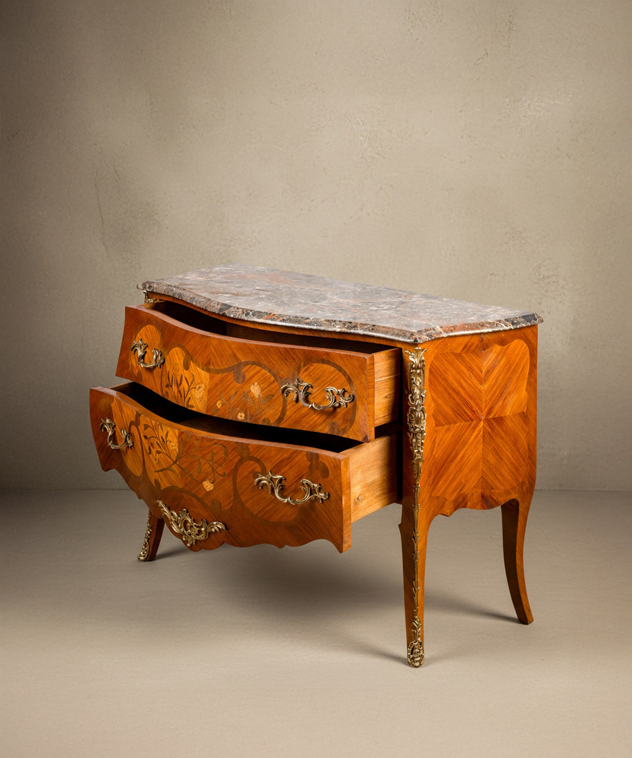 Cómoda francesa bombé estilo Luis XV con marquetería floral y tapa de mármol vista frontal tres cuartos.