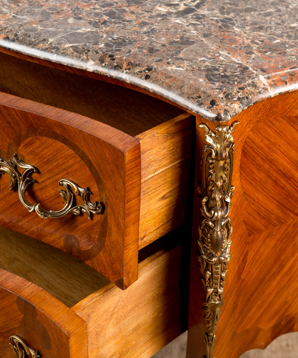 Cómoda francesa bombé estilo Luis XV con marquetería floral y tapa de mármol vista frontal tres cuartos.