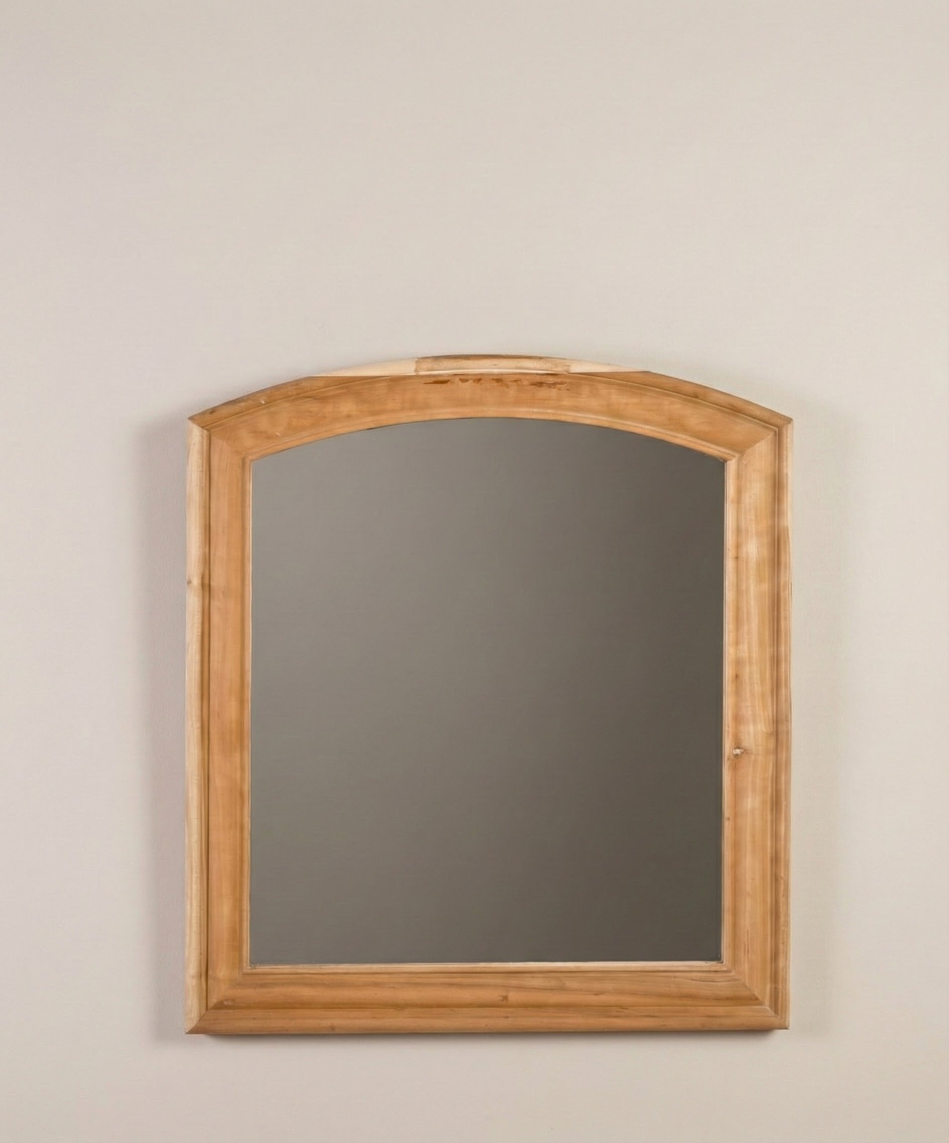 Detalle del marco de madera color miel del espejo con forma de arco