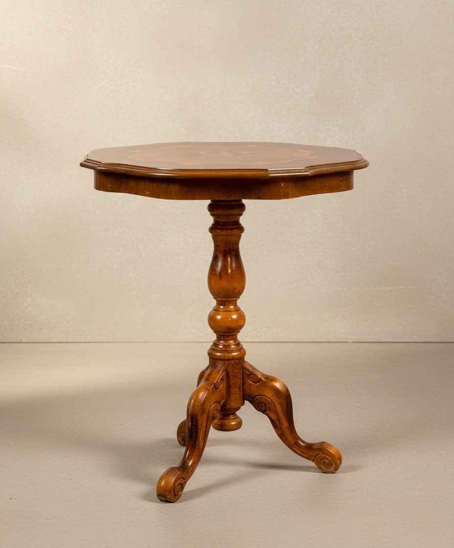 Vista frontal de mesa velador antigua de madera noble con pie central torneado sobre fondo neutro.