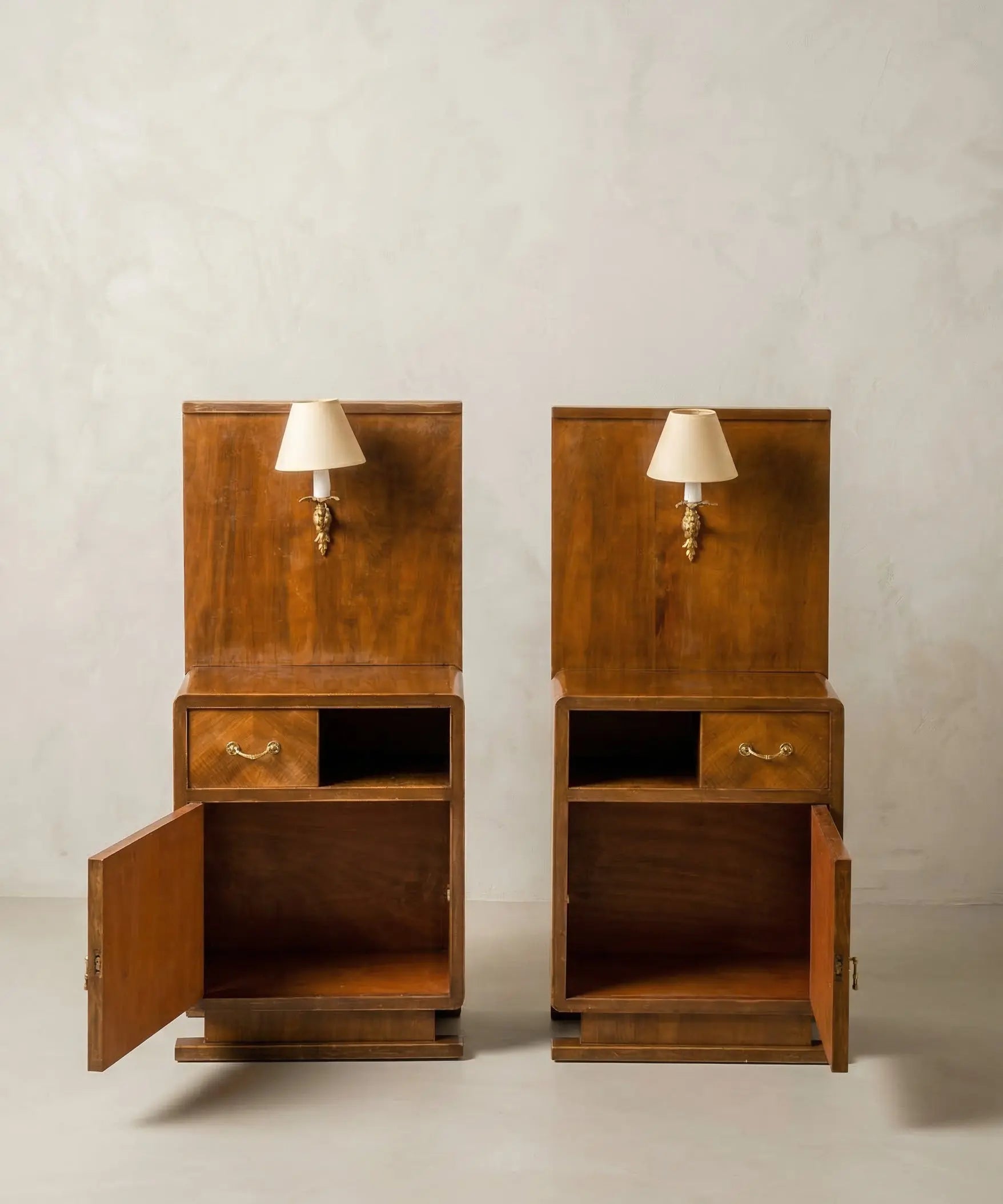 Mesitas de cama antiguas simétricas con puertas abiertas y estantes de almacenaje.