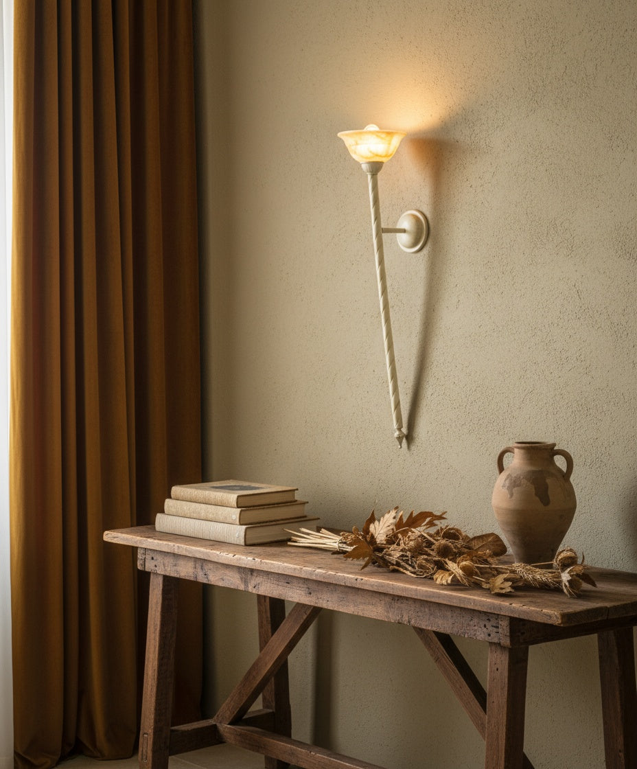 Detalle del soporte circular a la pared y la voluta decorativa del aplique de metal.