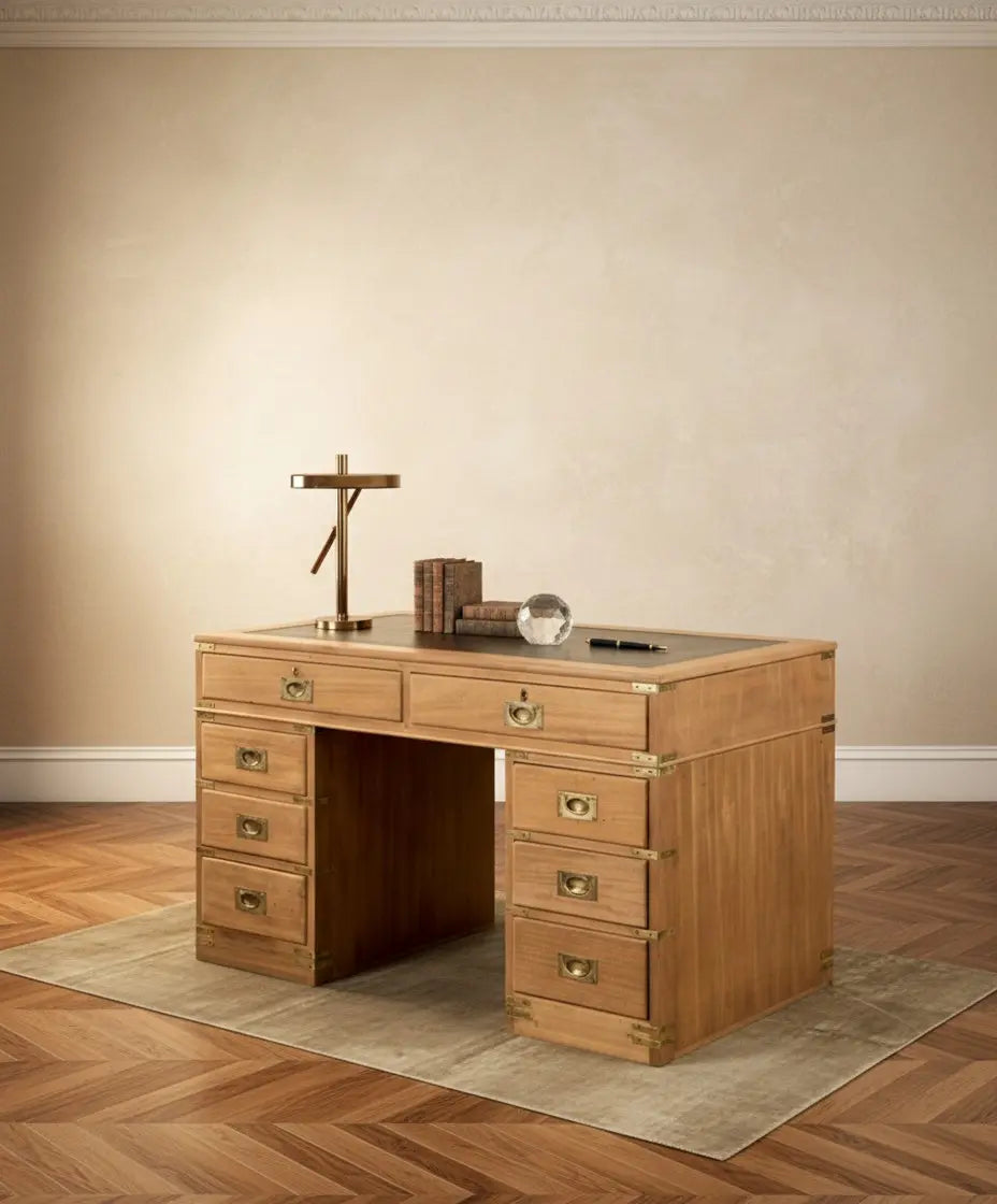 Escritorio de campaña inglés de madera clara con ocho cajones y sobre de cuero verde en ambiente de estudio.