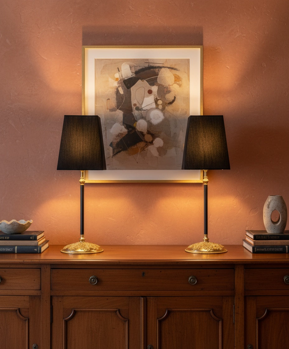 Pareja de lámparas flanqueando cuadro abstracto sobre aparador clásico, iluminación cálida ambiental.