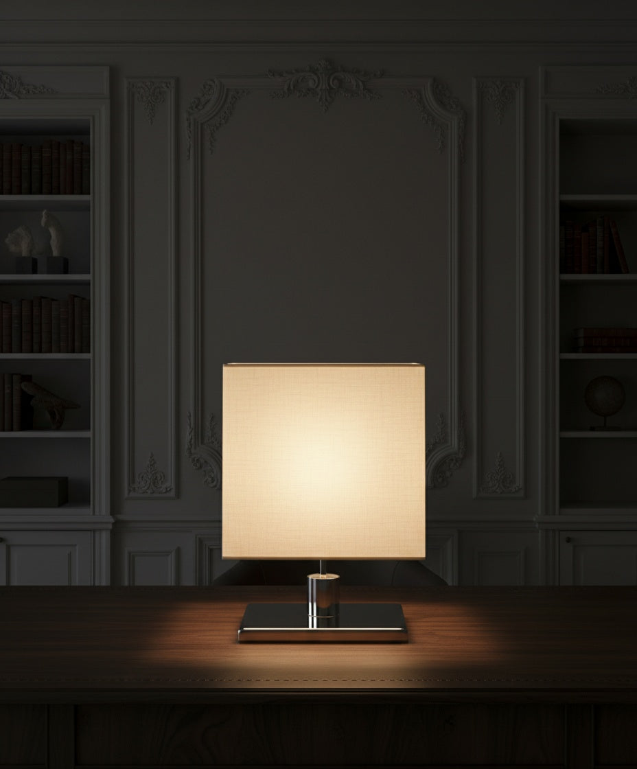 Lámpara Épure encendida en ambiente de biblioteca clásica, mostrando la calidez del haz de luz sobre madera.