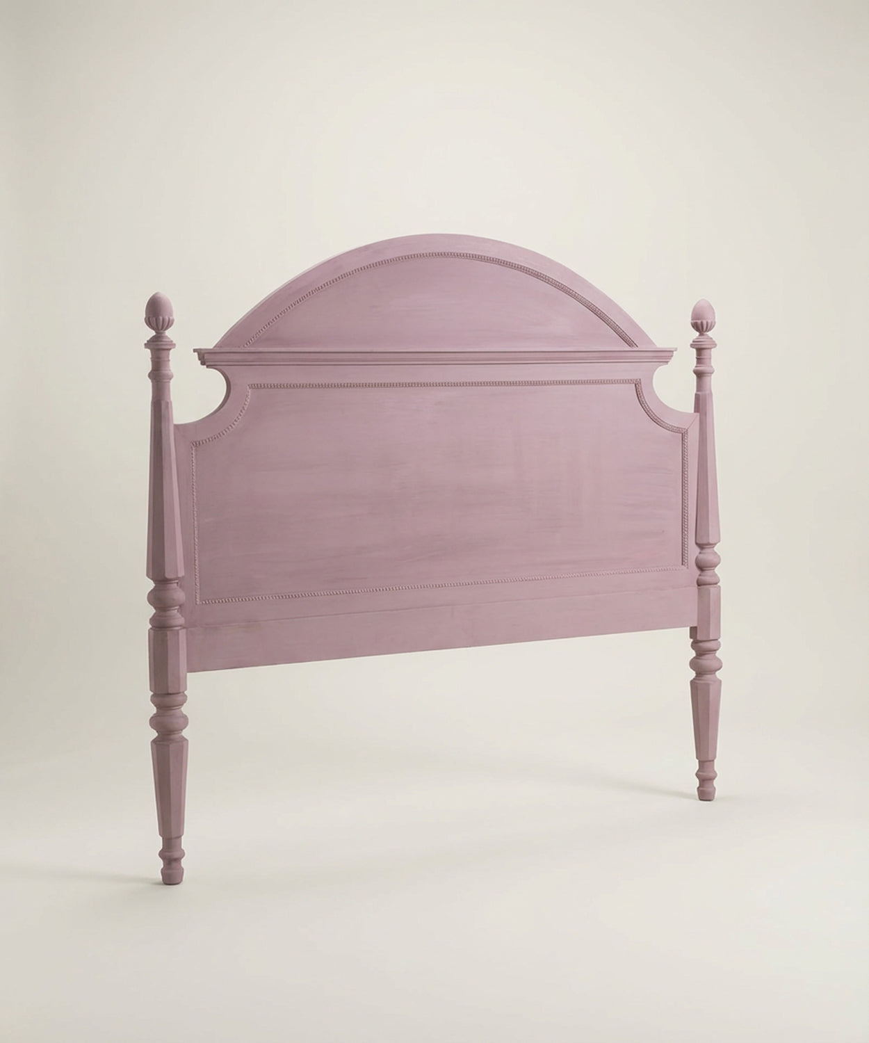 Vista en perspectiva del cabecero rosa mostrando el grosor de los postes y las molduras decorativas