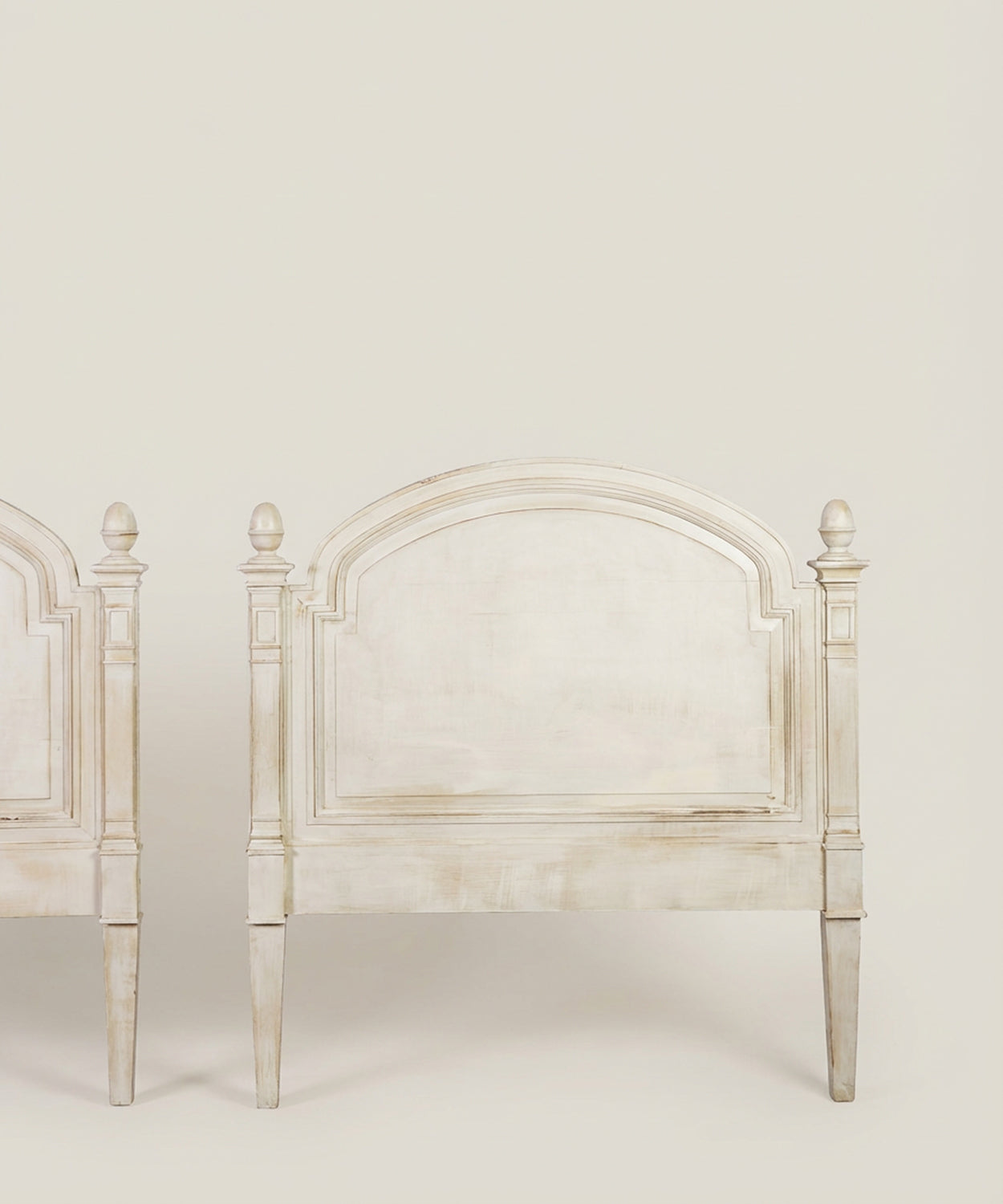 Detalle de cabecero de madera blanca con acabado envejecido y molduras clásicas