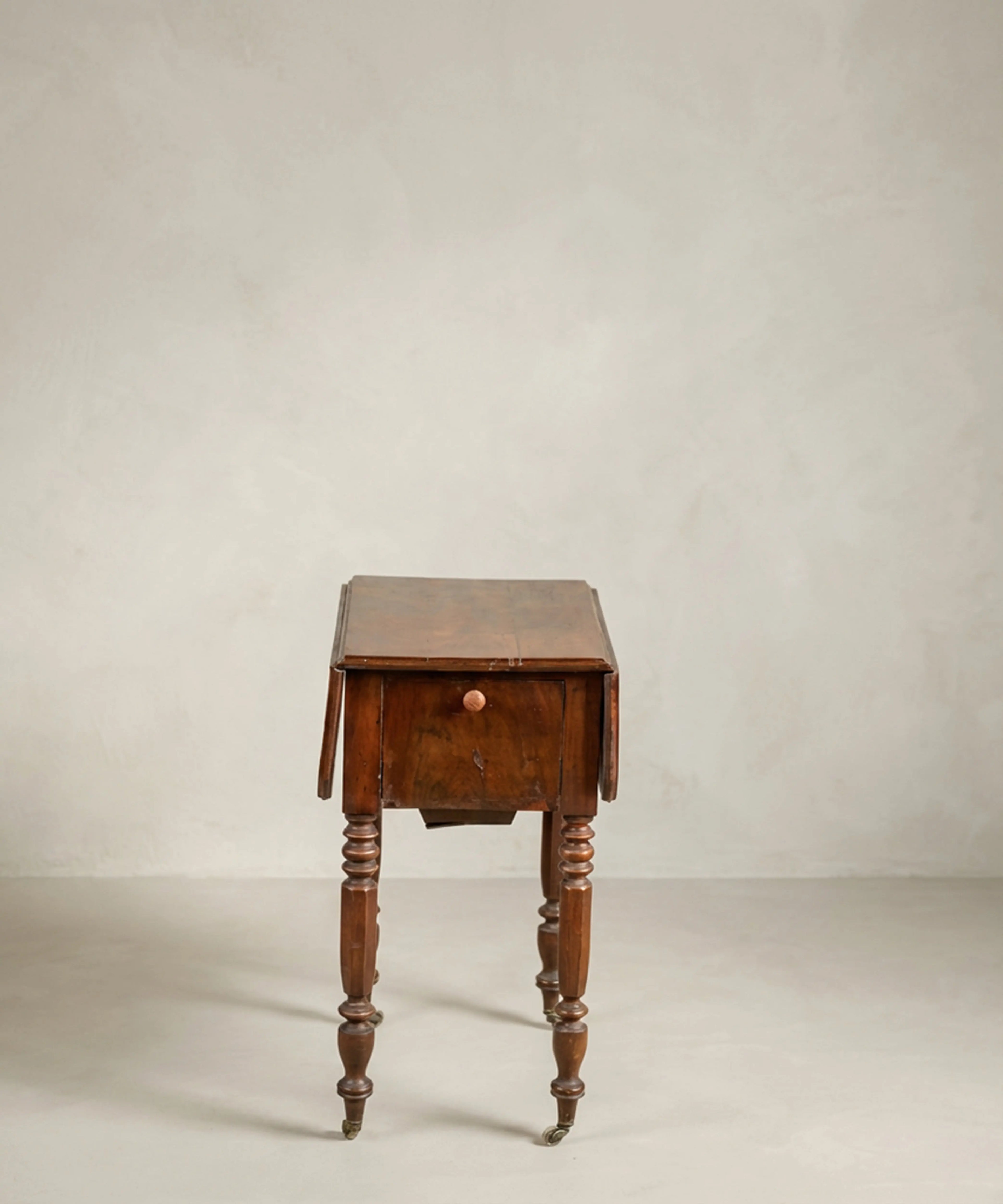 Mesa costurero antigua victoriana de caoba con patas torneadas y ruedas.