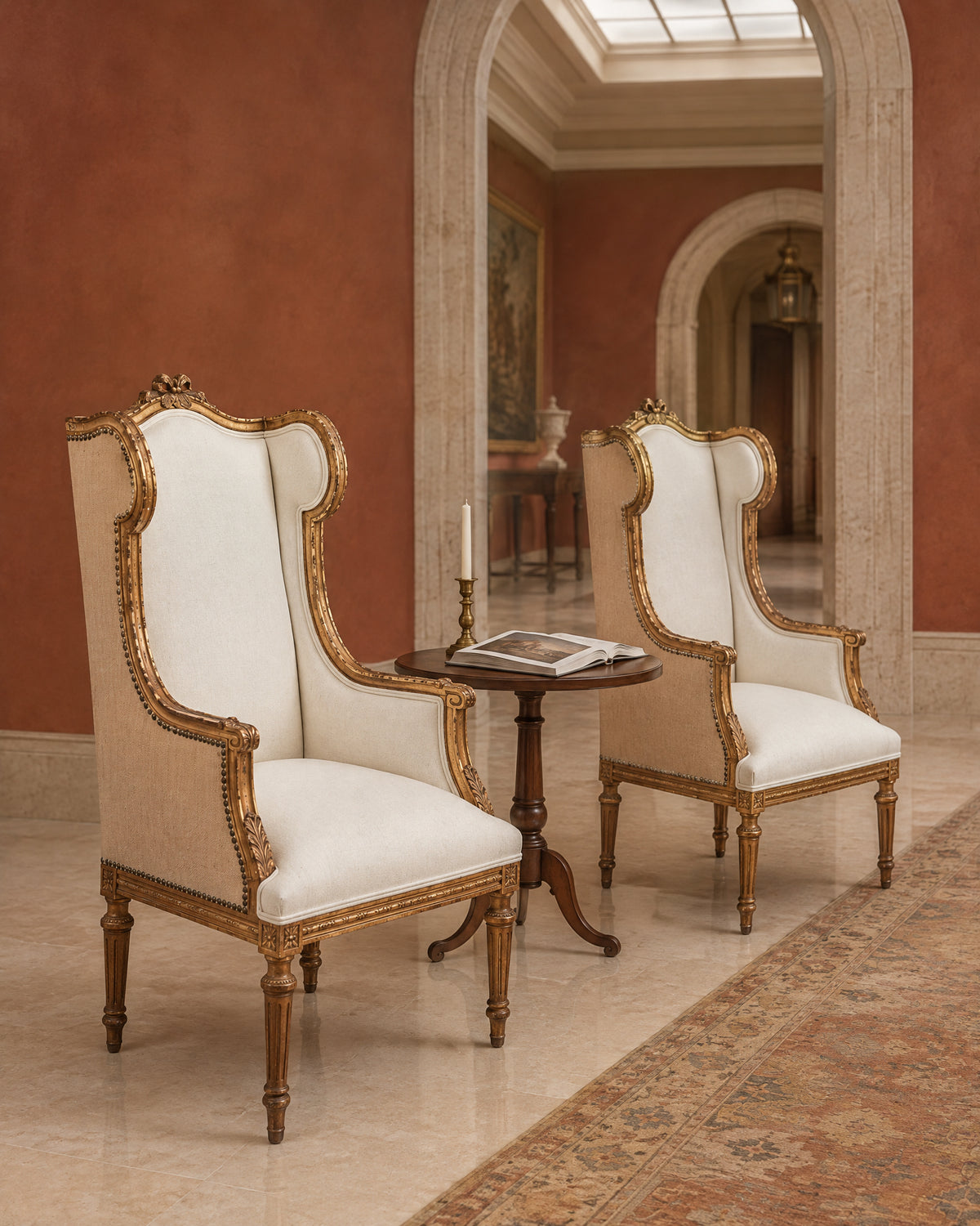 Pareja de sillones orejeros Luis XVI dorados en galería con muro rojo y arco de travertino — Antique Arte y Decoración