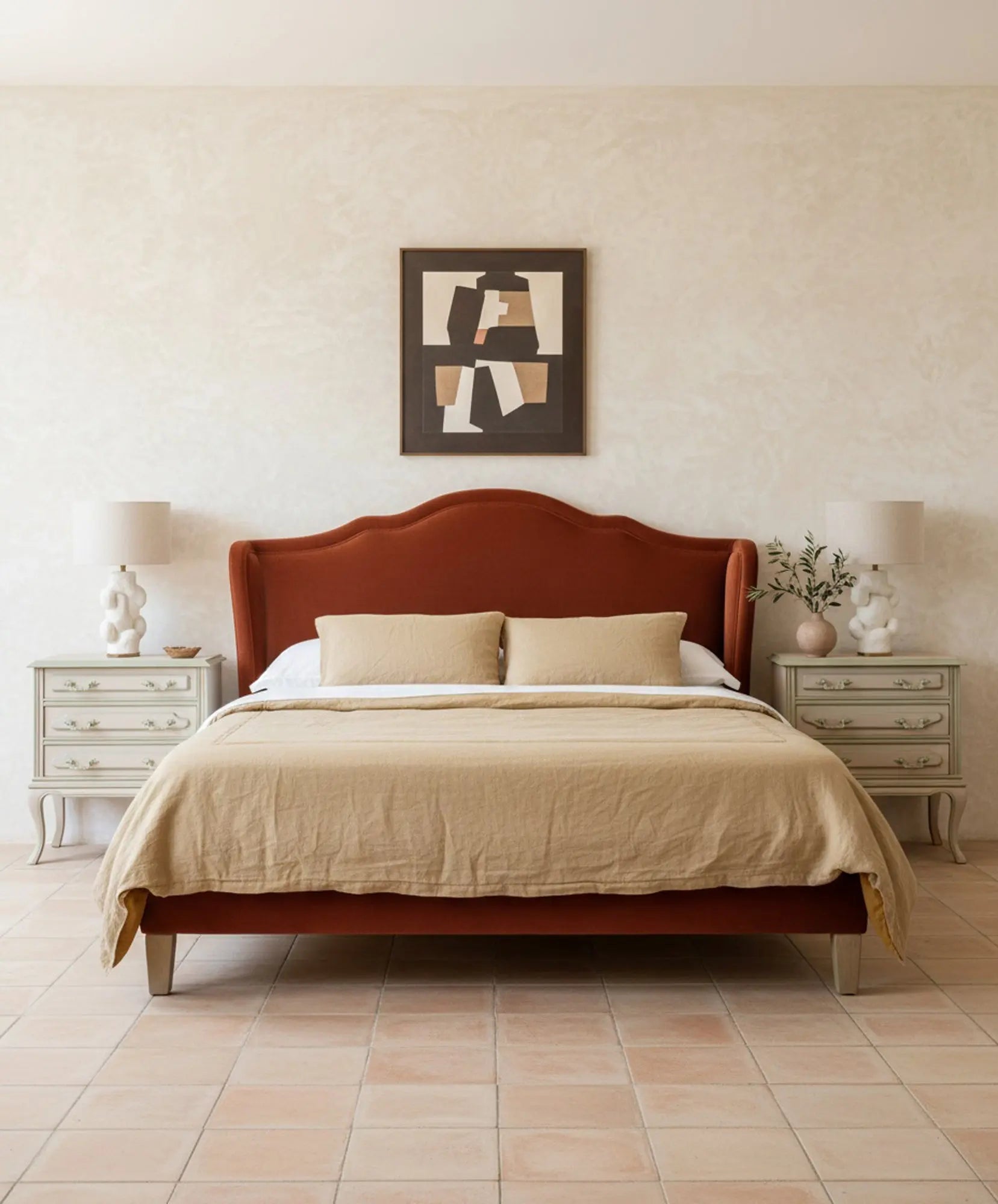 Dormitorio decorado con cama de cabecero terracota y dos mesillas de noche clásicas restauradas.