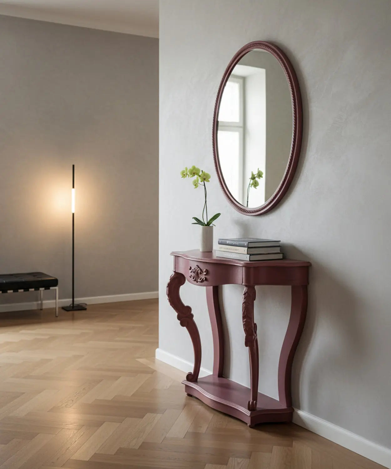 Consola estilo francés en un pasillo moderno con paredes grises, espejo ovalado y decoración floral minimalista