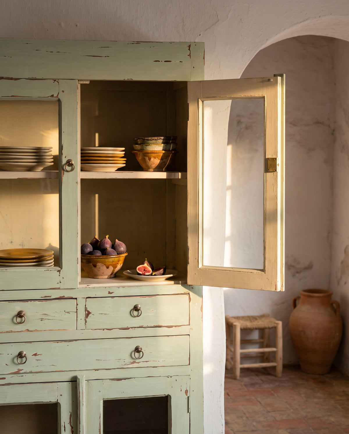 Alacena vitrina verde decapé abierta en cocina con vajilla e higos — Antique Arte y Decoración
