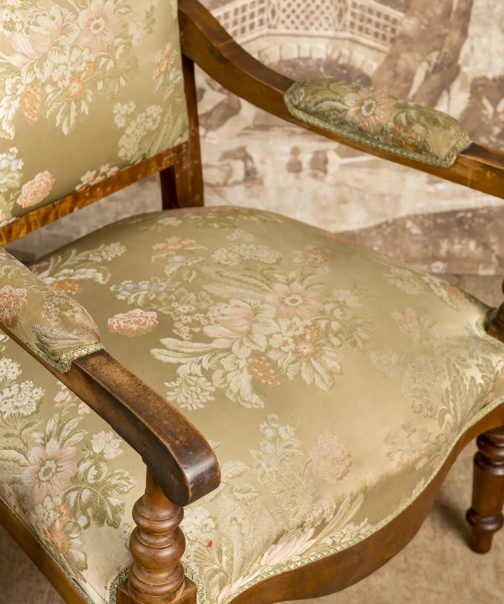 Primer plano de la talla en el copete y el tejido jacquard floral en tonos pastel de los sillones.