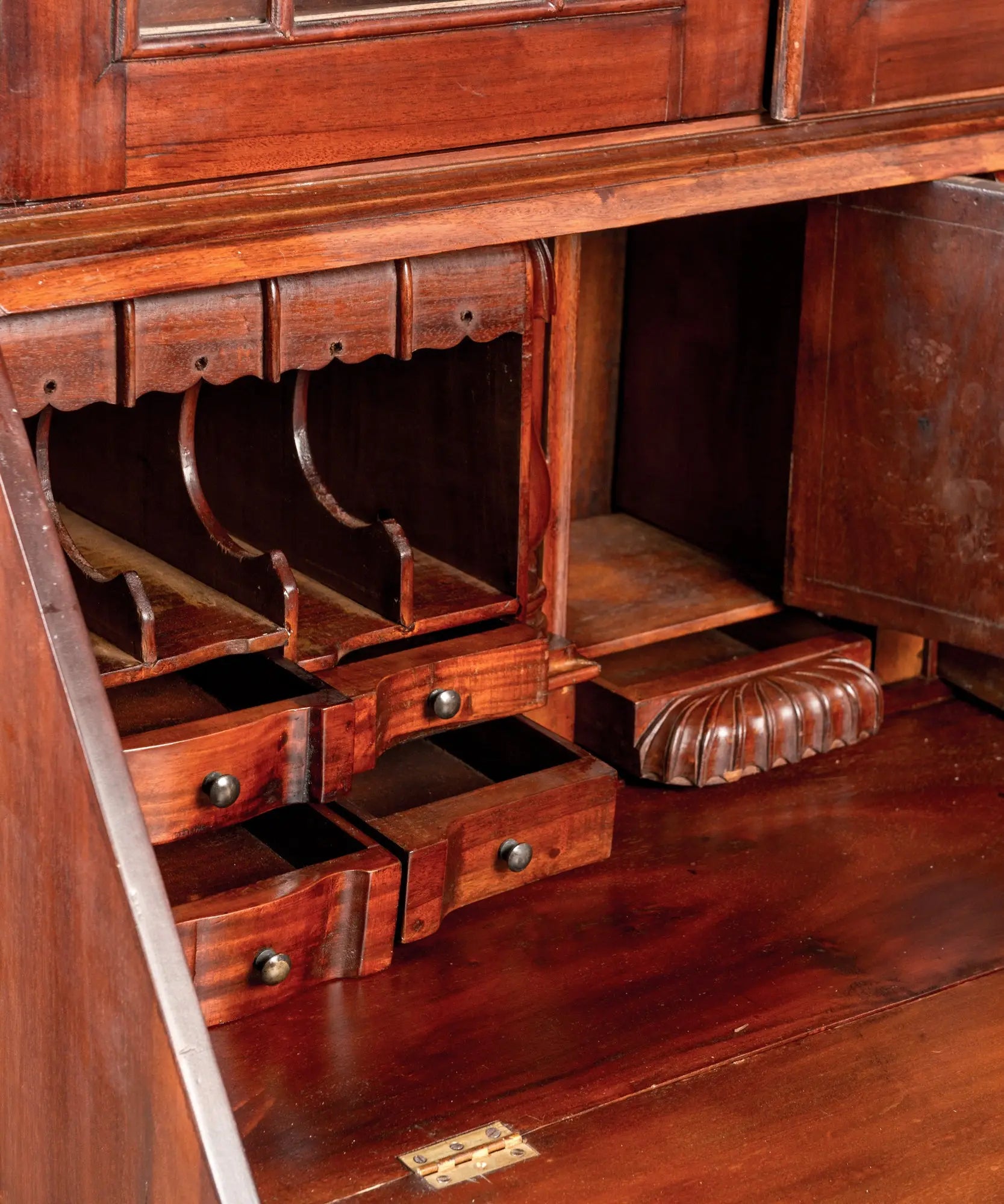 Primer plano del interior del escritorio (secretaria) mostrando cajones pequeños, nichos para cartas y puerta central con marquetería.