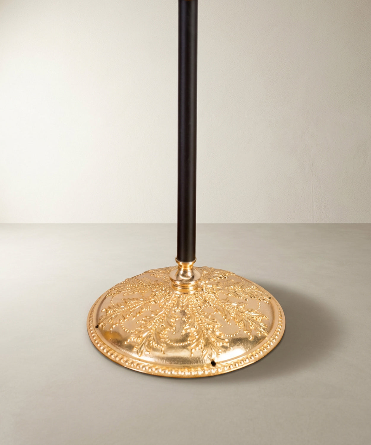 Close-up de la base de bronce con relieves de hojas de acanto y pátina envejecida.