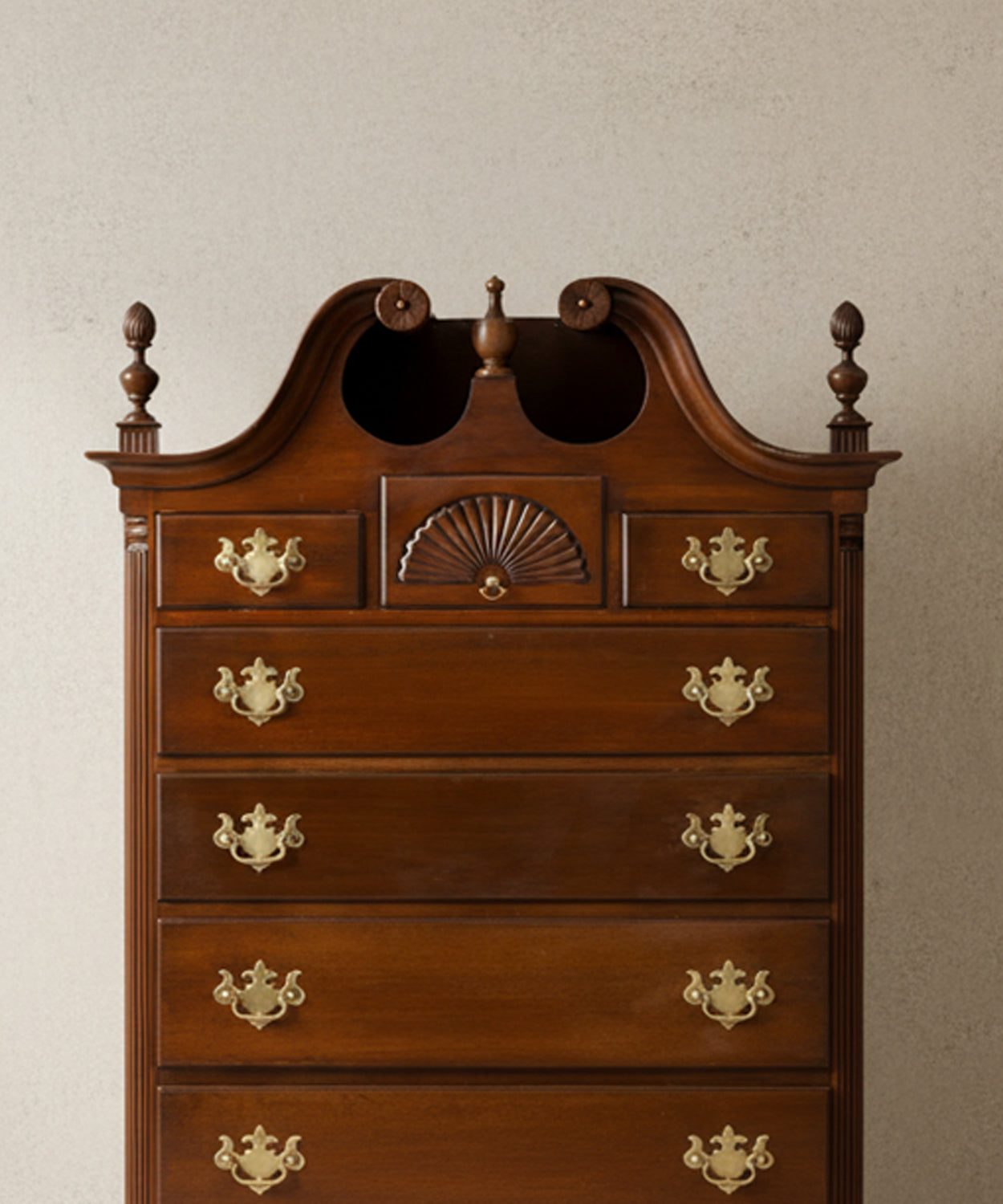 Primer plano de los cajones de caoba mostrando los tiradores de latón y la talla de concha.