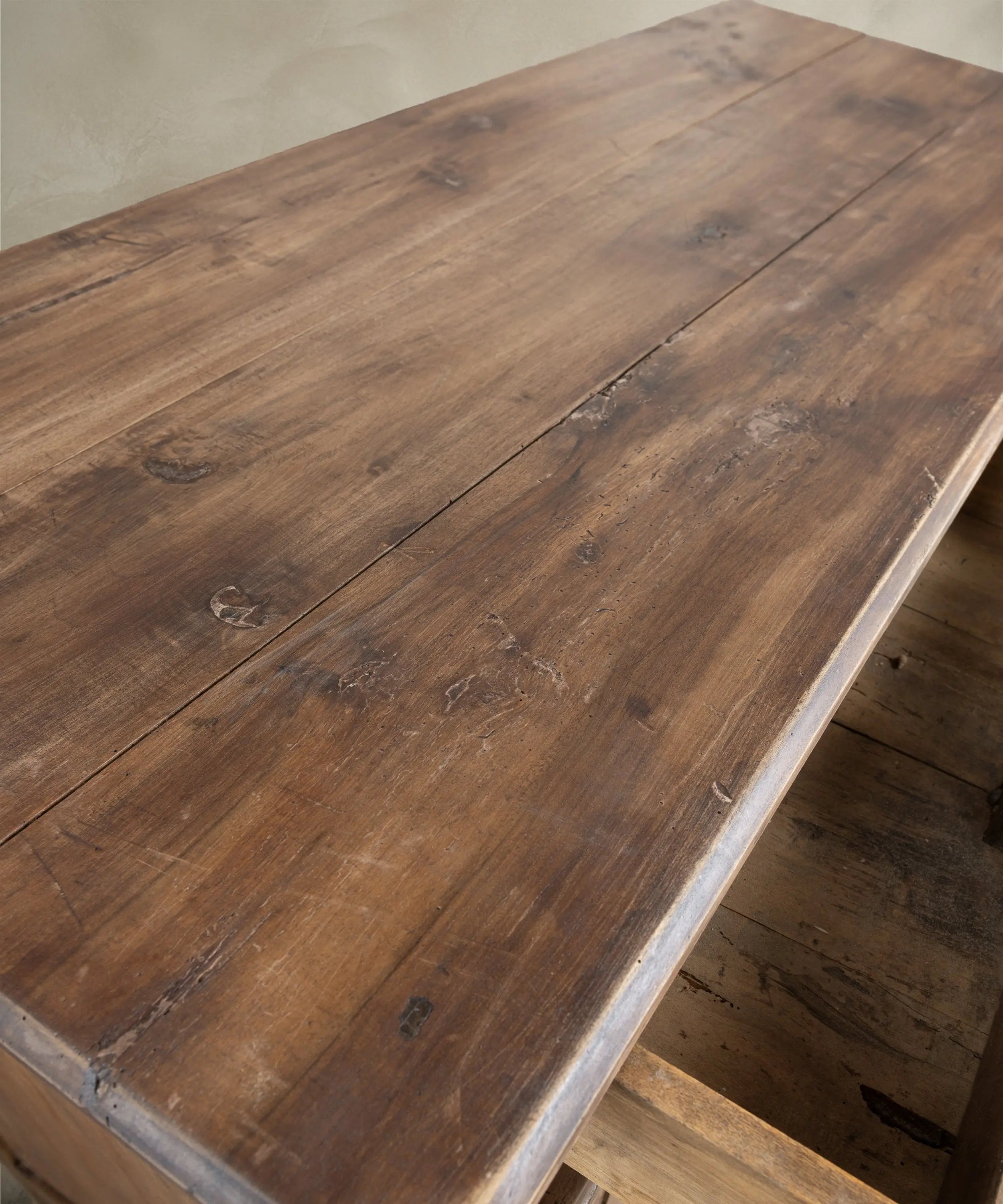 Encimera rústica de tablones de madera cruda con nudos e imperfecciones naturales en mueble antiguo.