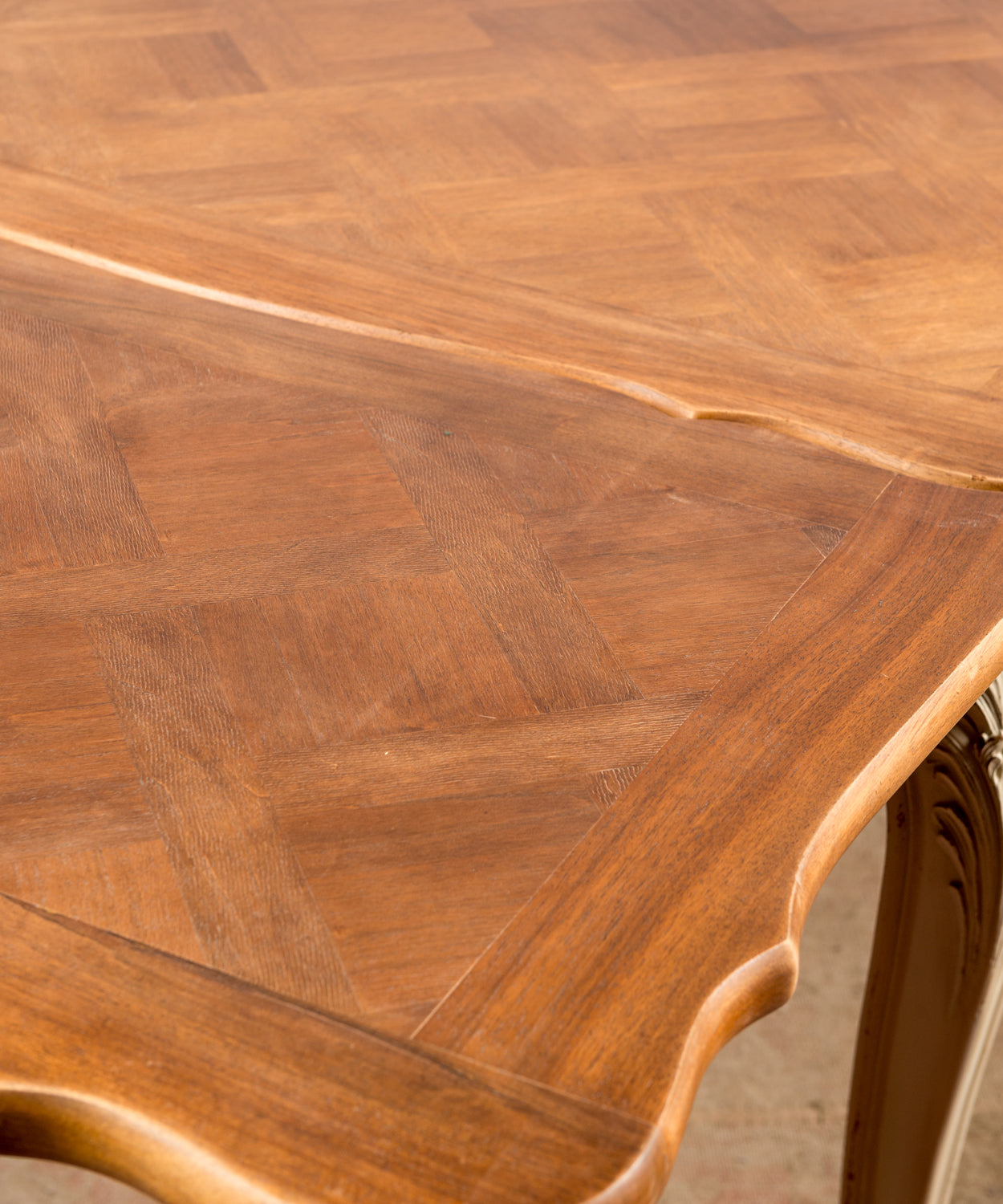 Primer plano del faldón tallado con motivo de concha y patas cabriolé en pátina crema.