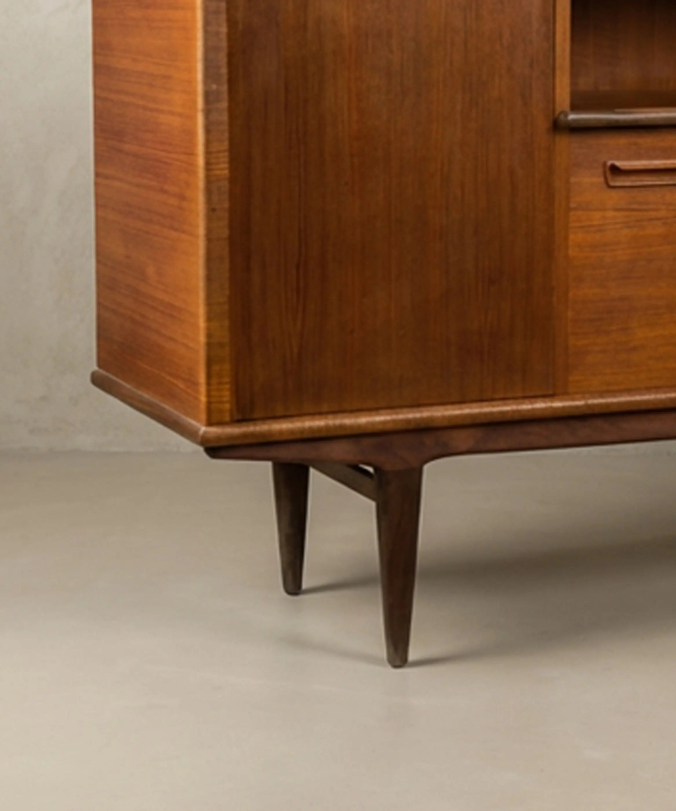 Aparador vintage de madera de teca resaltando los tiradores orgánicos y las patas cónicas.