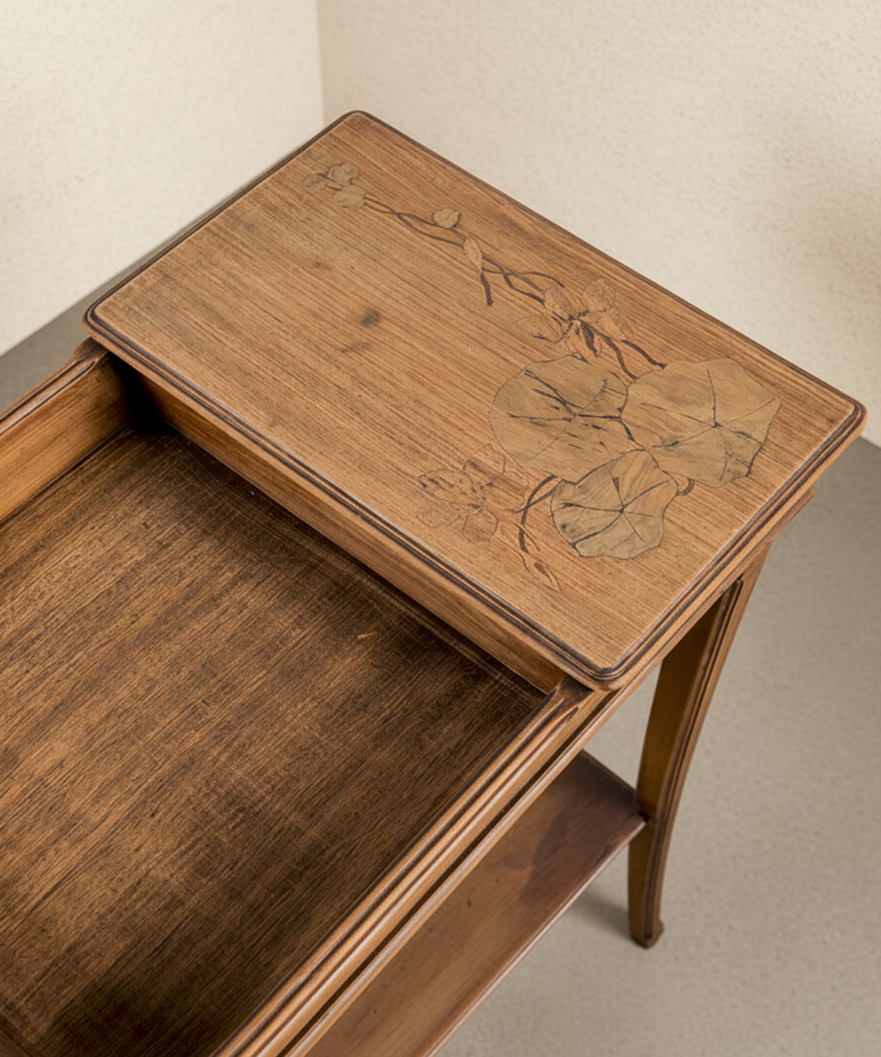 Primer plano de la marquetería floral artesanal en la tapa de madera noble.