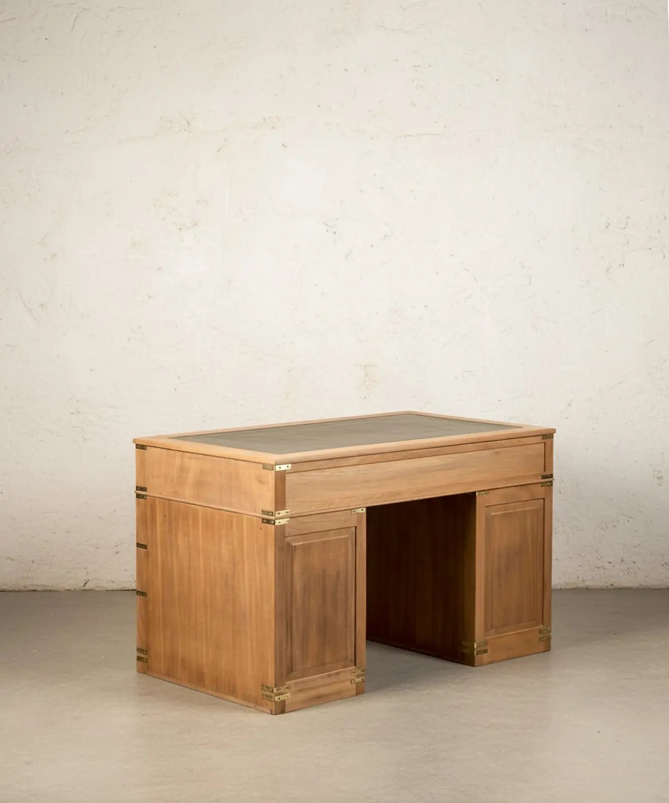 Escritorio de campaña inglés de madera clara con ocho cajones y sobre de cuero verde en ambiente de estudio.