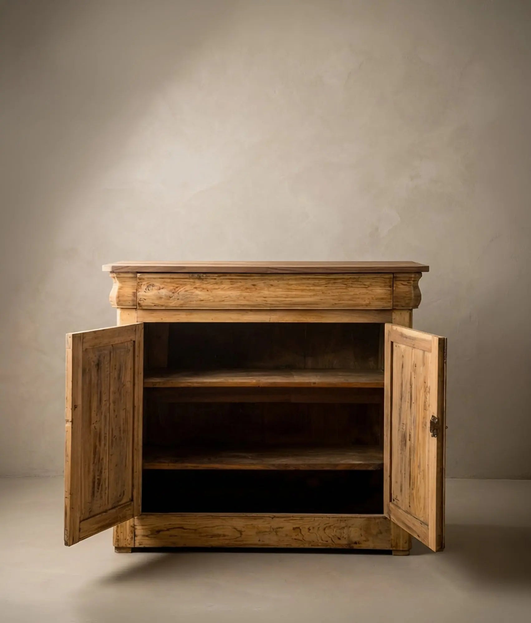 Aparador antiguo de madera clara estilo Luis Felipe con dos puertas y cajón superior integrado.