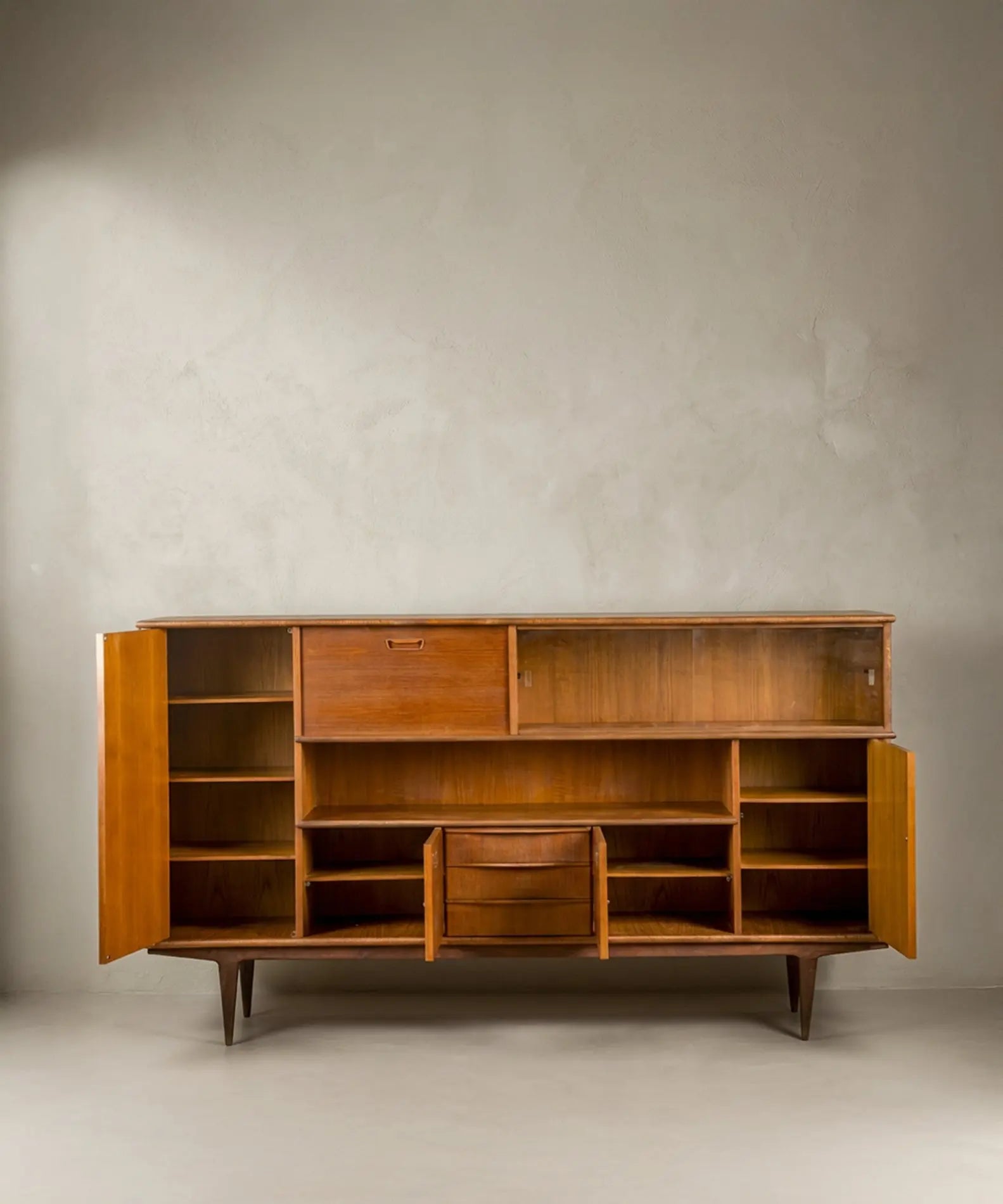 Interior del aparador Mid-Century mostrando compartimentos de almacenamiento, cajones y estantes de madera.