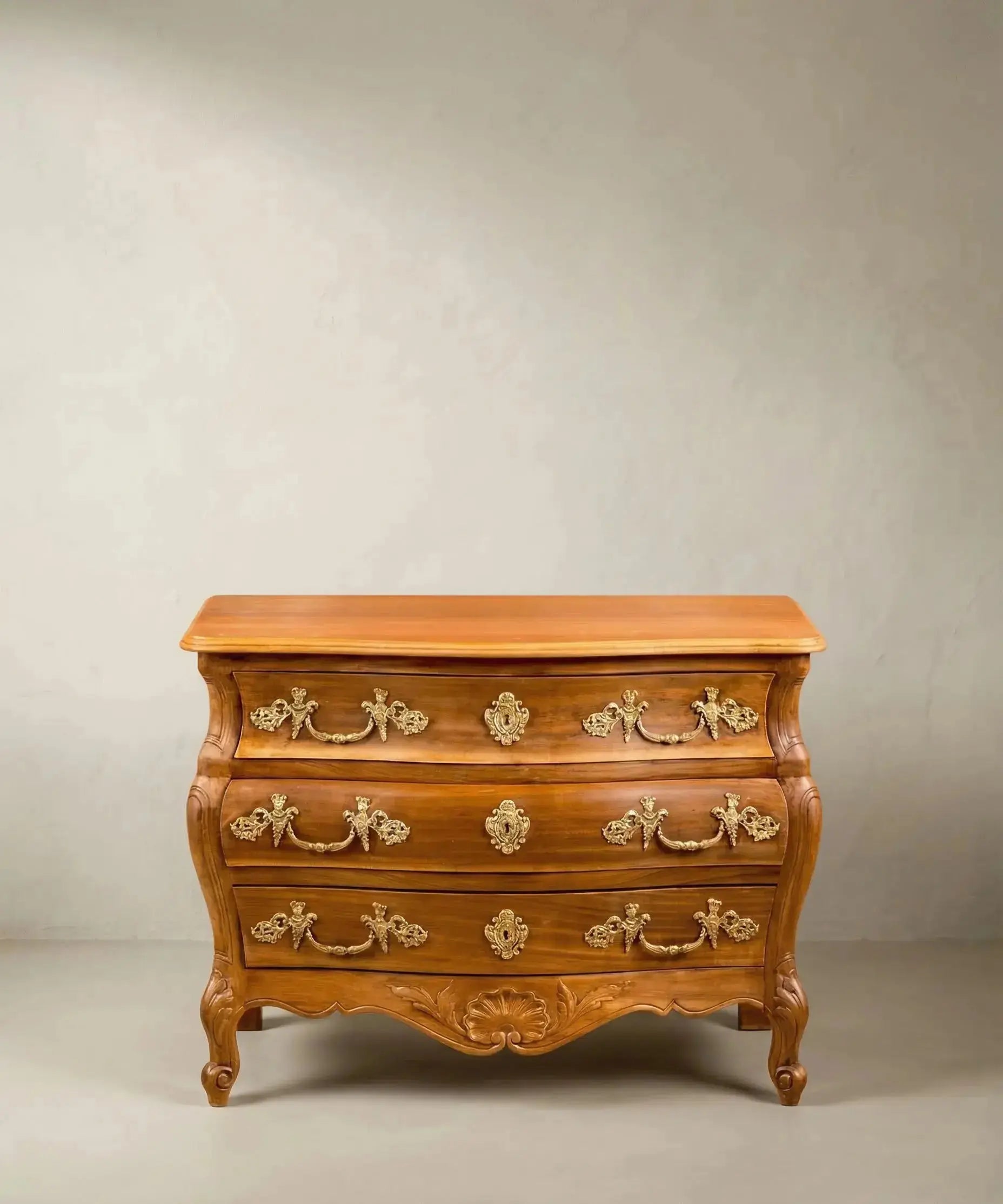 Cómoda bombé vintage de madera estilo Luis XV con bronces dorados y patas curvas.
