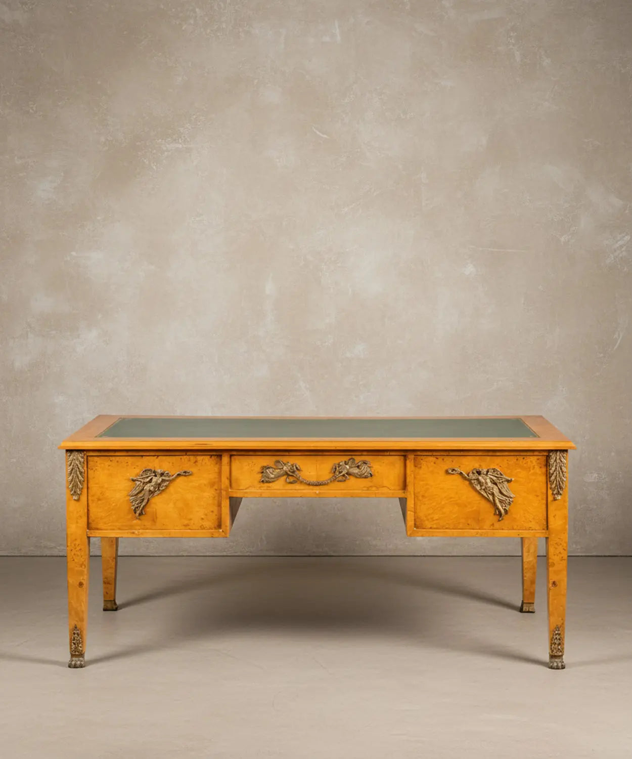 Escritorio estilo Imperio en madera de raíz con cinco cajones y tapete de piel verde frontal.