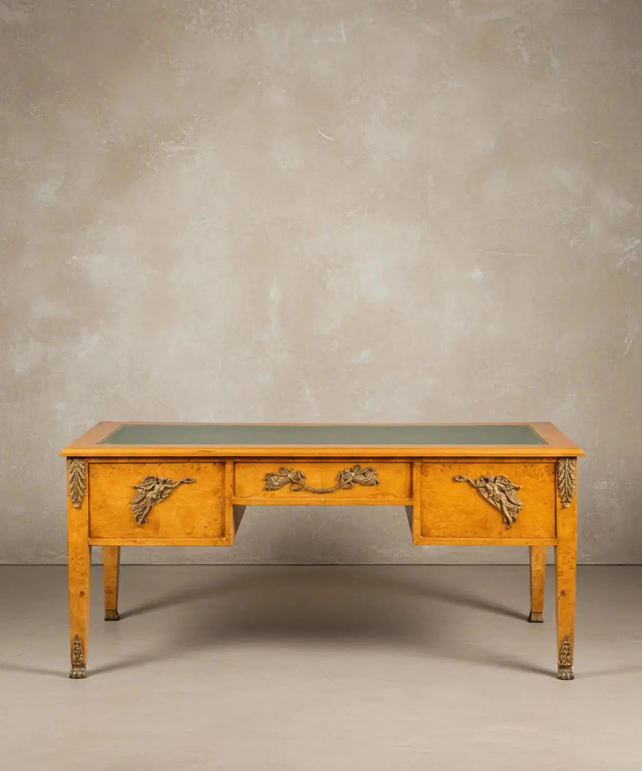 Escritorio estilo Imperio en madera de raíz con cinco cajones y tapete de piel verde frontal.