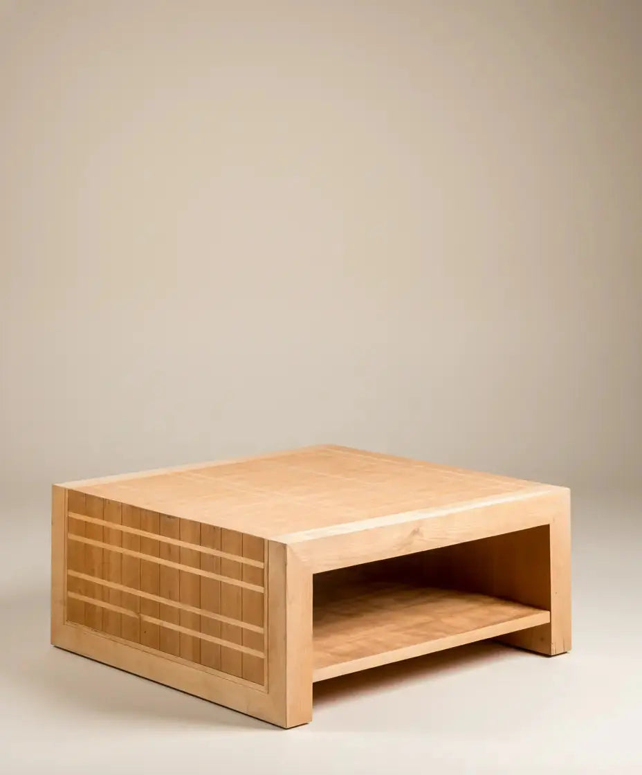 Mesa de centro de madera clara artesanal mostrando su estante inferior y el detalle geométrico lateral.