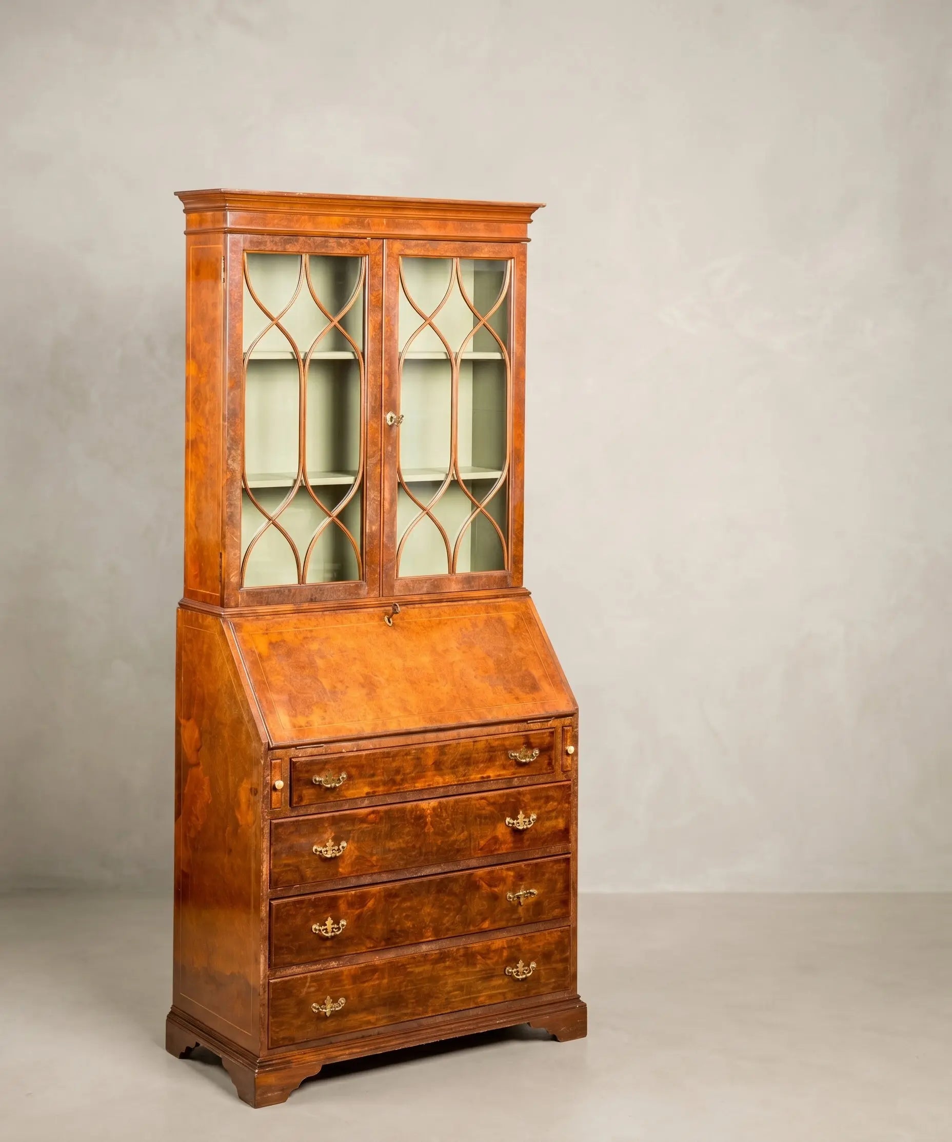 Vista frontal completa del bureau-bookcase inglés antiguo en raíz de nogal, con la vitrina cerrada y el escritorio cerrado.
