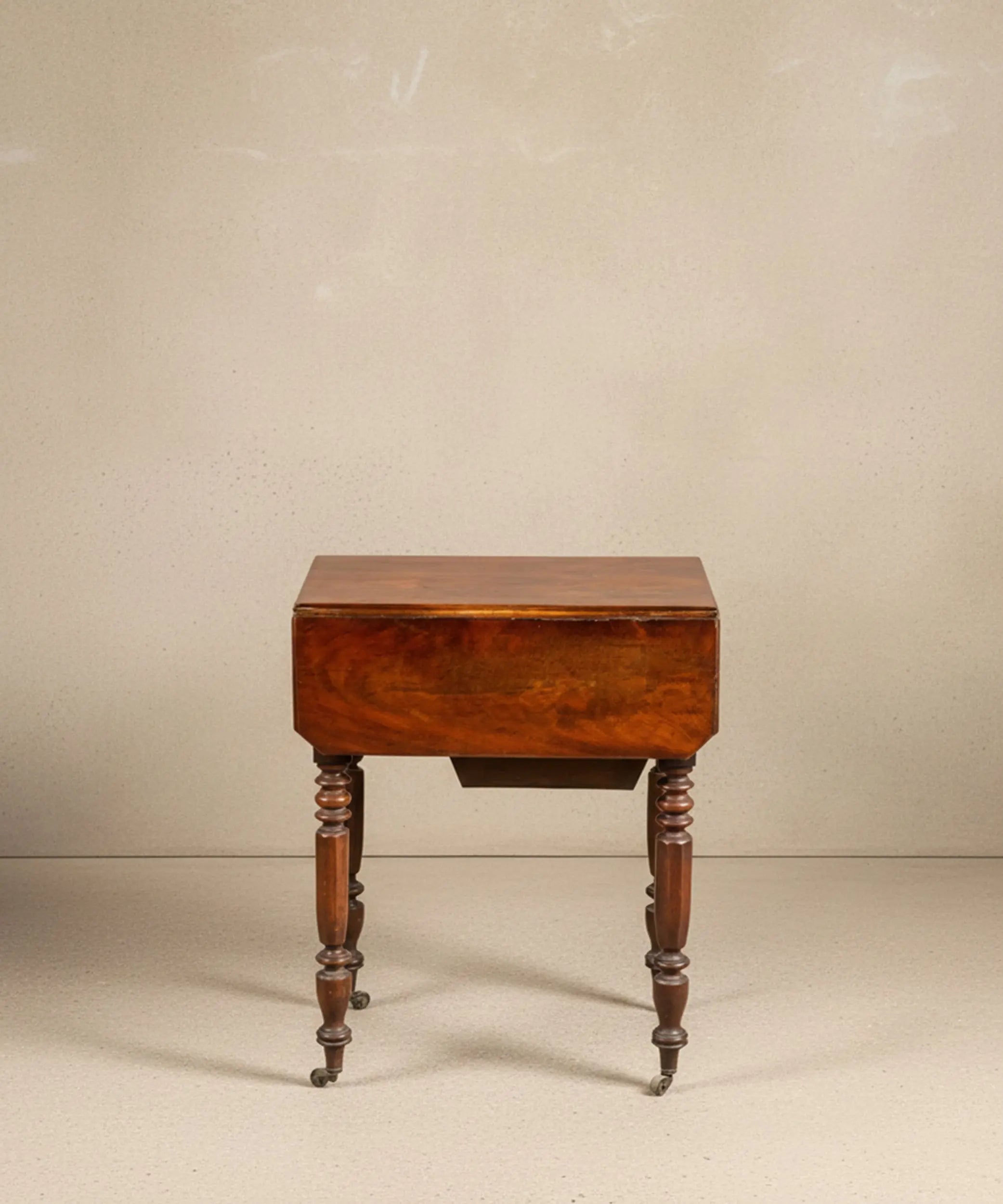 Mesa auxiliar de madera de caoba con alas laterales abatibles desplegadas.