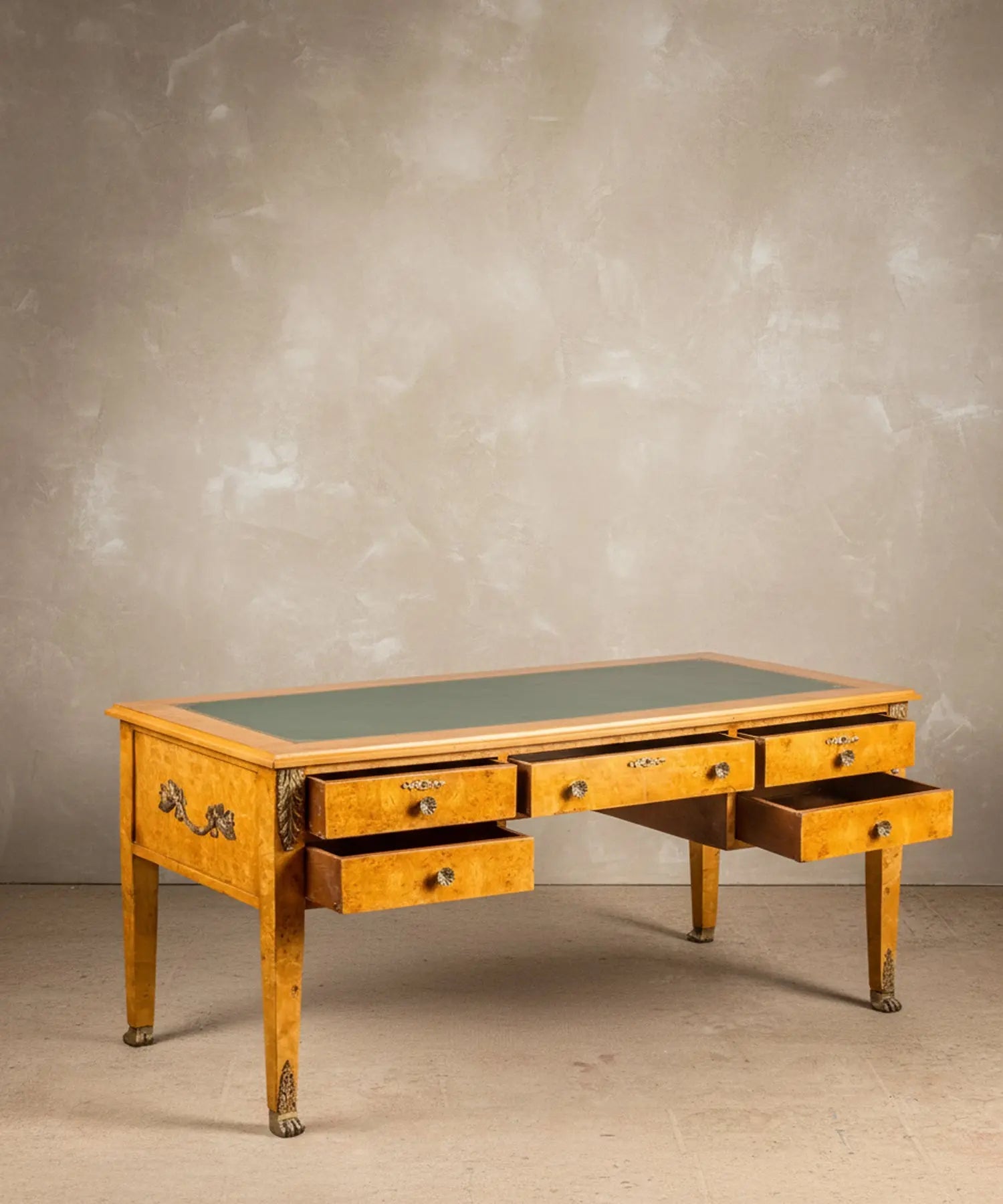 Vista angular del escritorio resaltando el veteado de la madera de raíz y los sabots de garra de león.