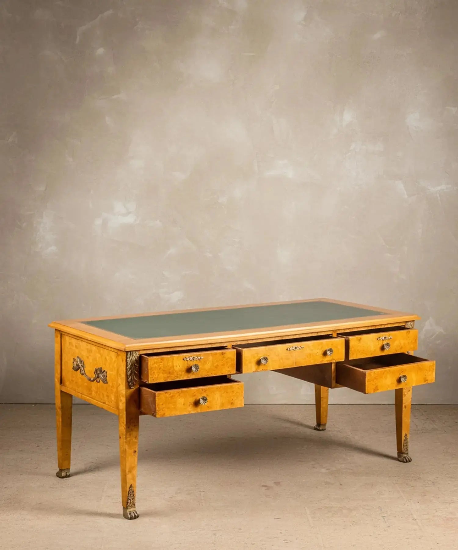 Vista angular del escritorio resaltando el veteado de la madera de raíz y los sabots de garra de león.