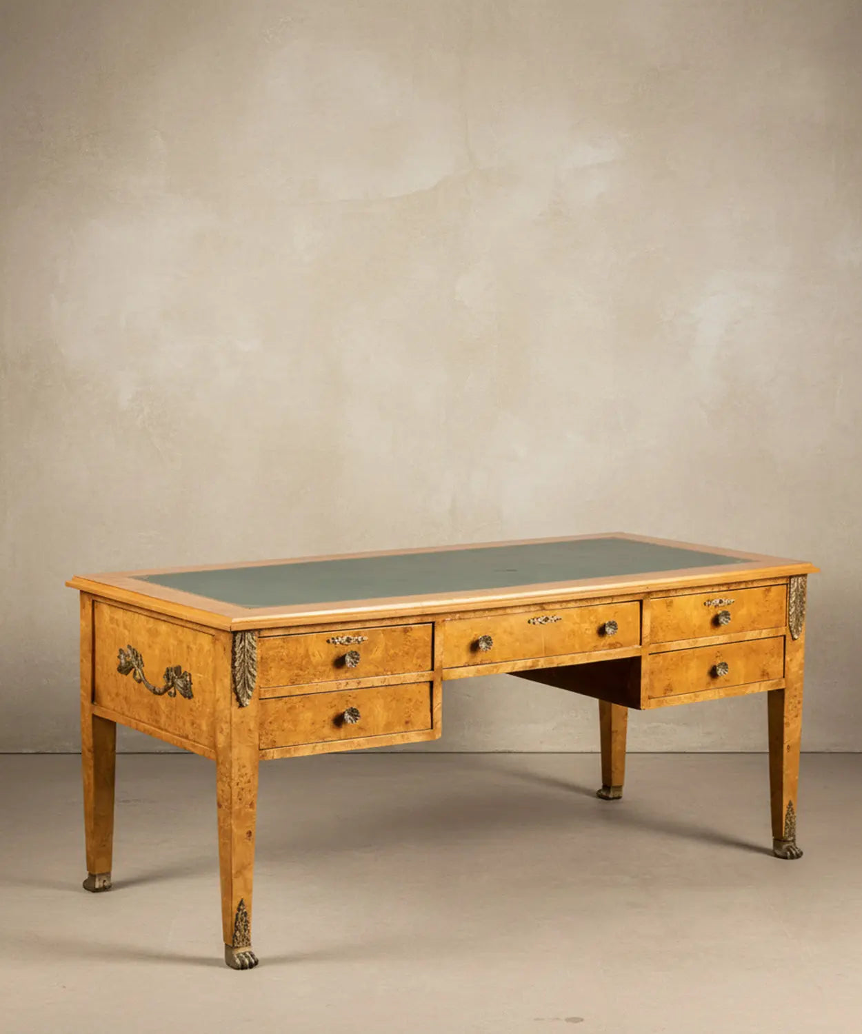 Vista angular del escritorio resaltando el veteado de la madera de raíz y los sabots de garra de león.