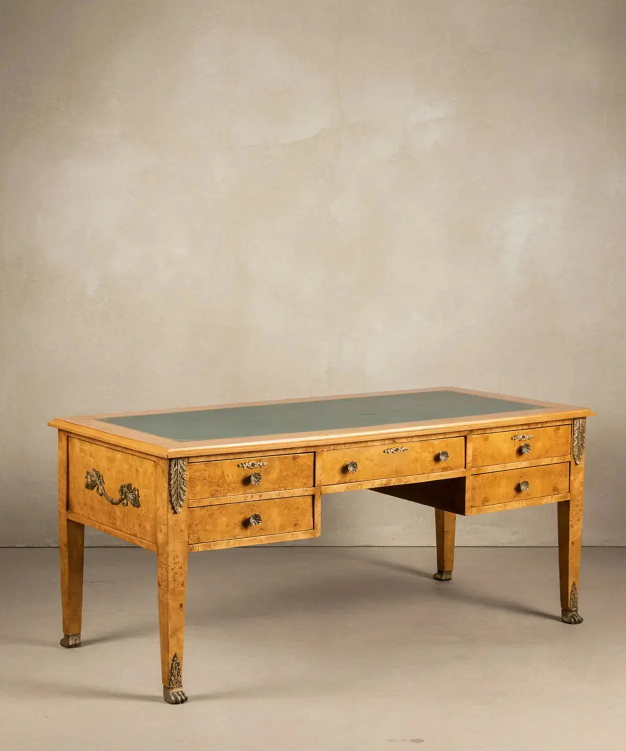 Vista angular del escritorio resaltando el veteado de la madera de raíz y los sabots de garra de león.