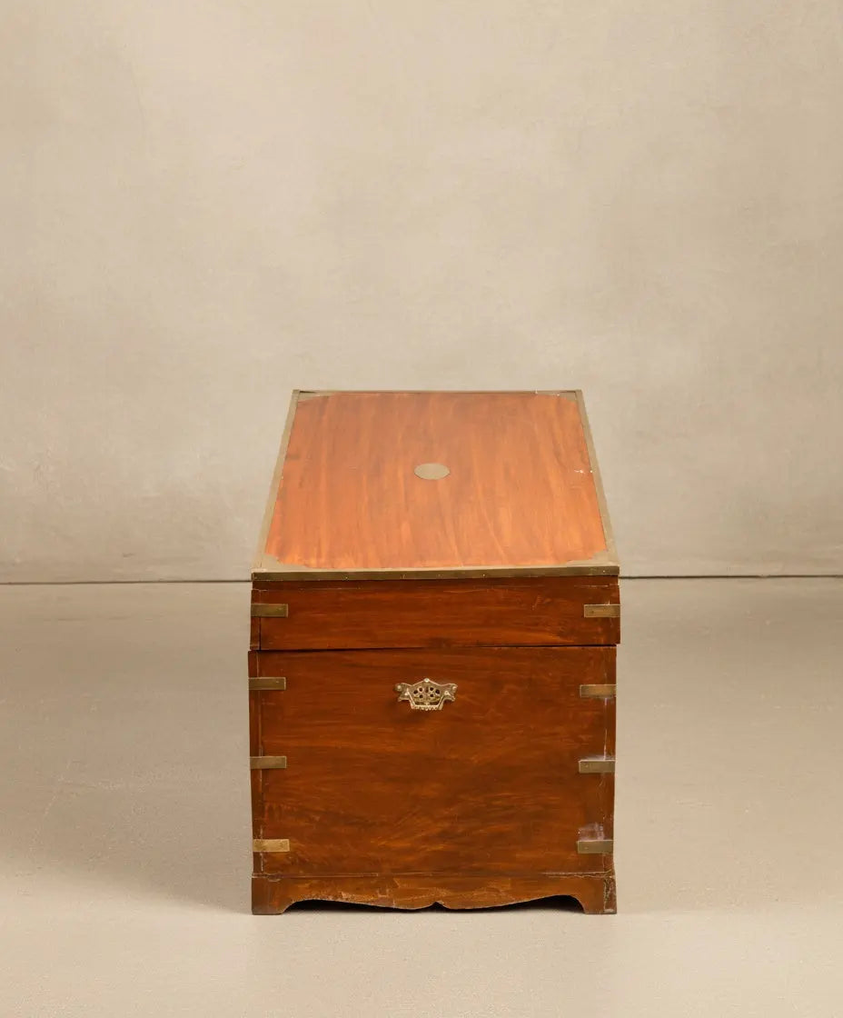 Baúl de campaña británico en madera de caoba cerrada, vista frontal mostrando herrajes de latón y veta natural.