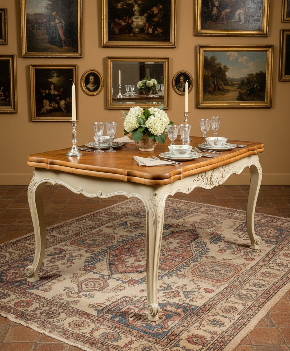 Ambiente cálido con la mesa francesa, alfombra oriental y cuadros antiguos de fondo.
