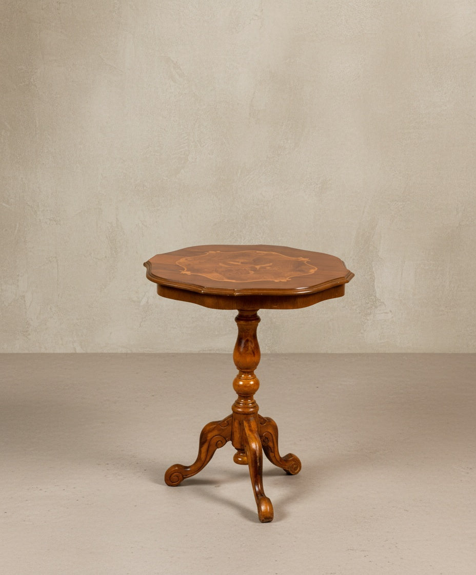 Vista frontal de mesa velador antigua de madera noble con pie central torneado sobre fondo neutro.