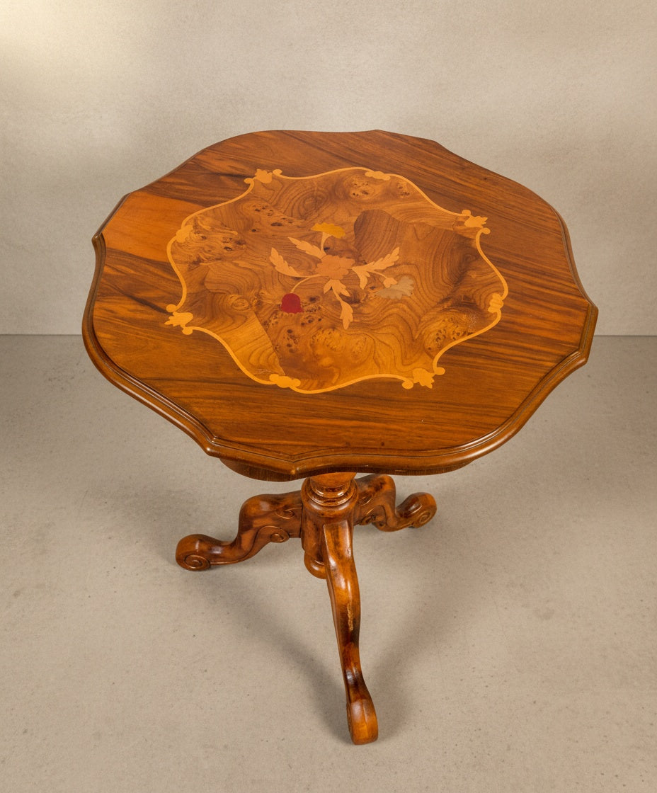 Vista superior de mesa velador antigua de madera noble con pie central torneado sobre fondo neutro.