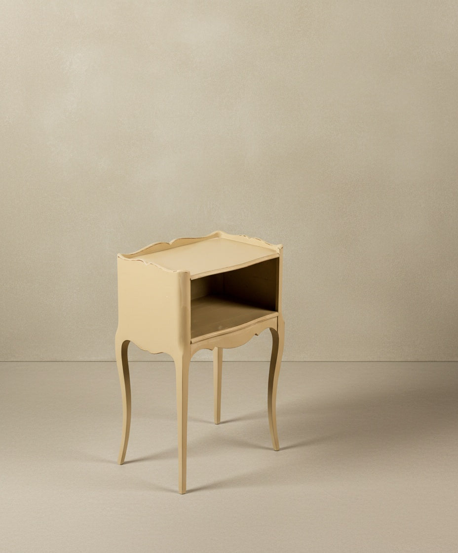 Mesilla de noche color beige con bordes festoneados y estructura esbelta francesa.