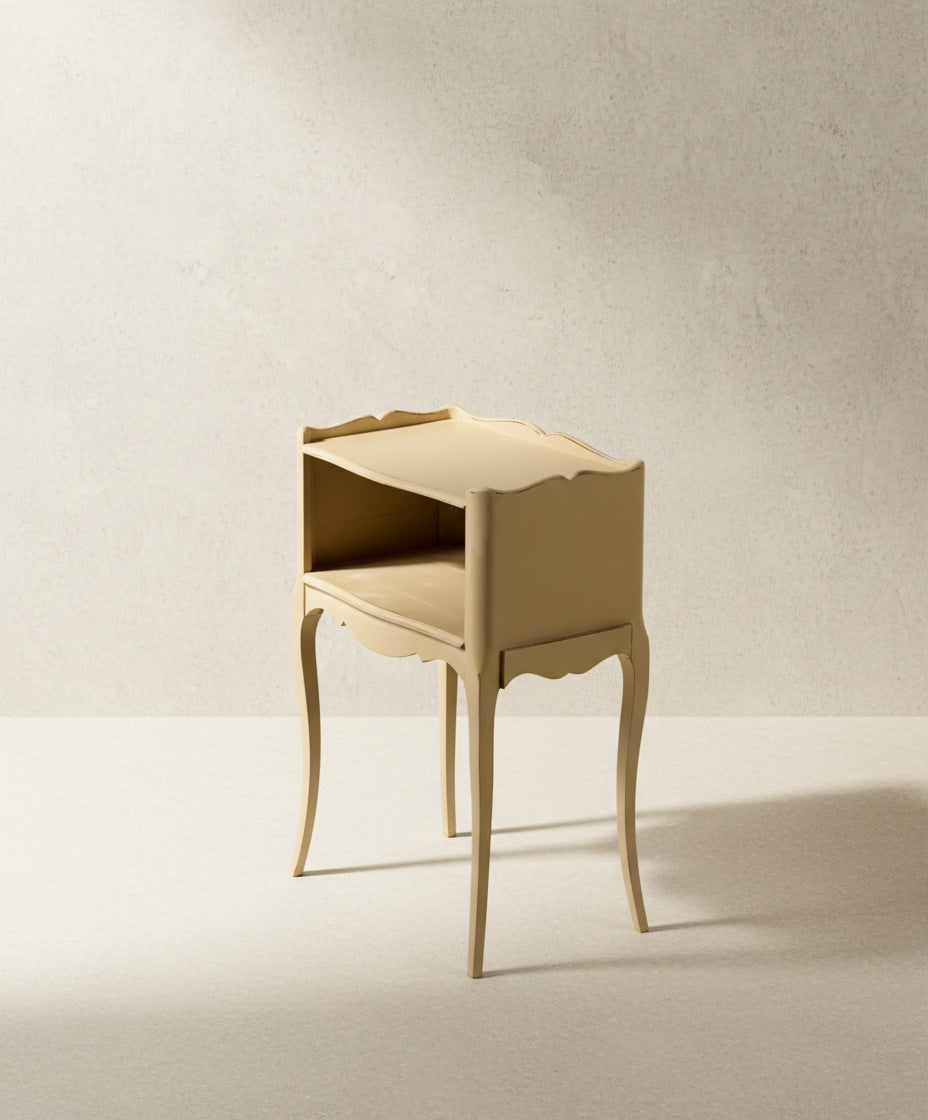 Mesilla de noche color beige con bordes festoneados y estructura esbelta francesa.