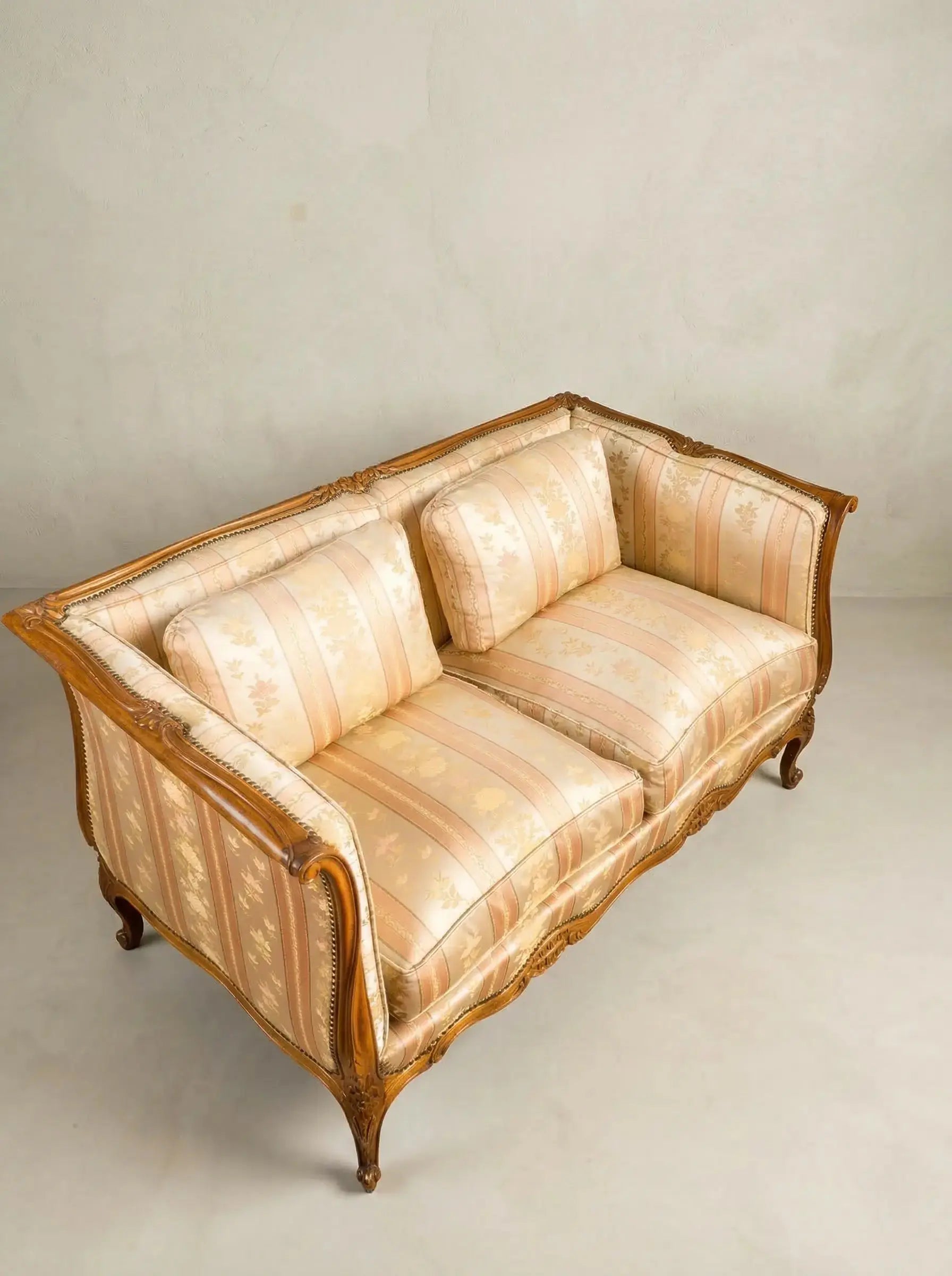 Vista superior de tapicería floral a rayas en tonos crema y melocotón de un sofá vintage.