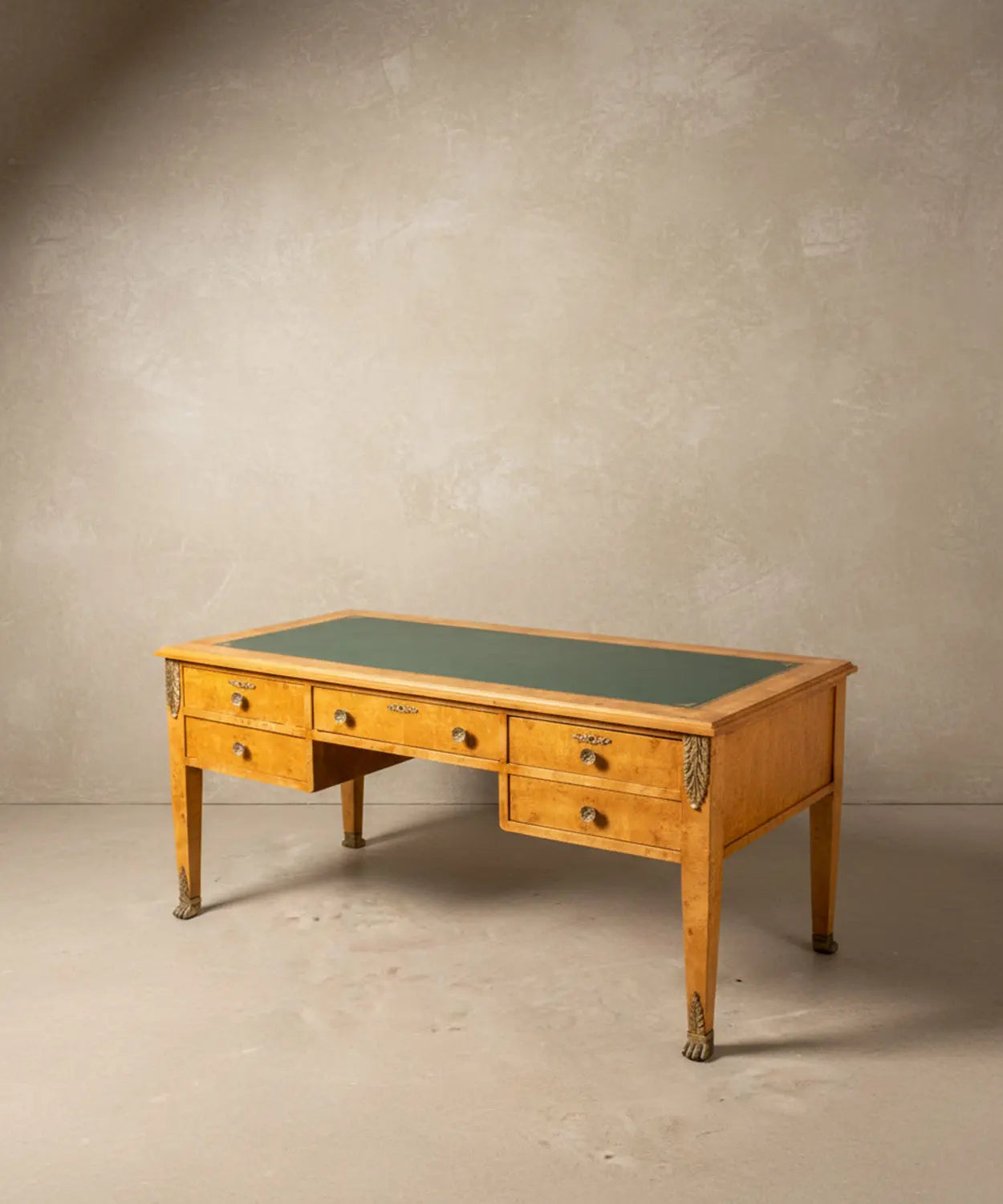 Vista angular del escritorio resaltando el veteado de la madera de raíz y los sabots de garra de león.