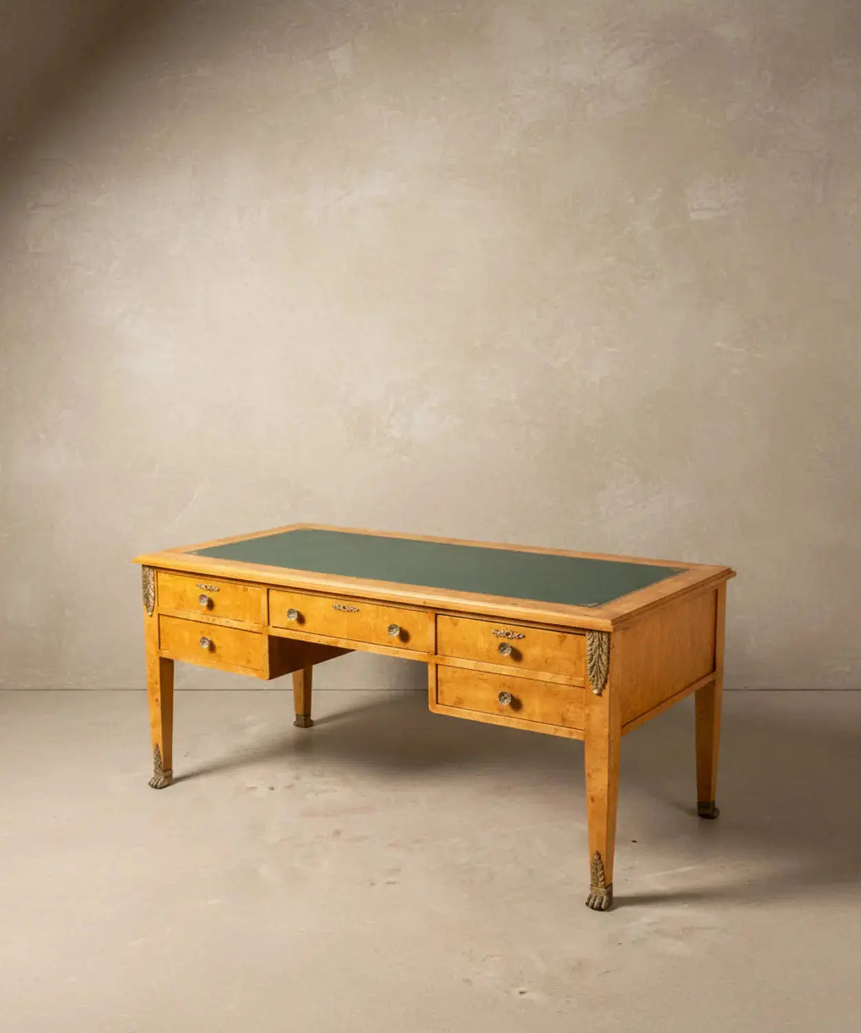 Vista angular del escritorio resaltando el veteado de la madera de raíz y los sabots de garra de león.